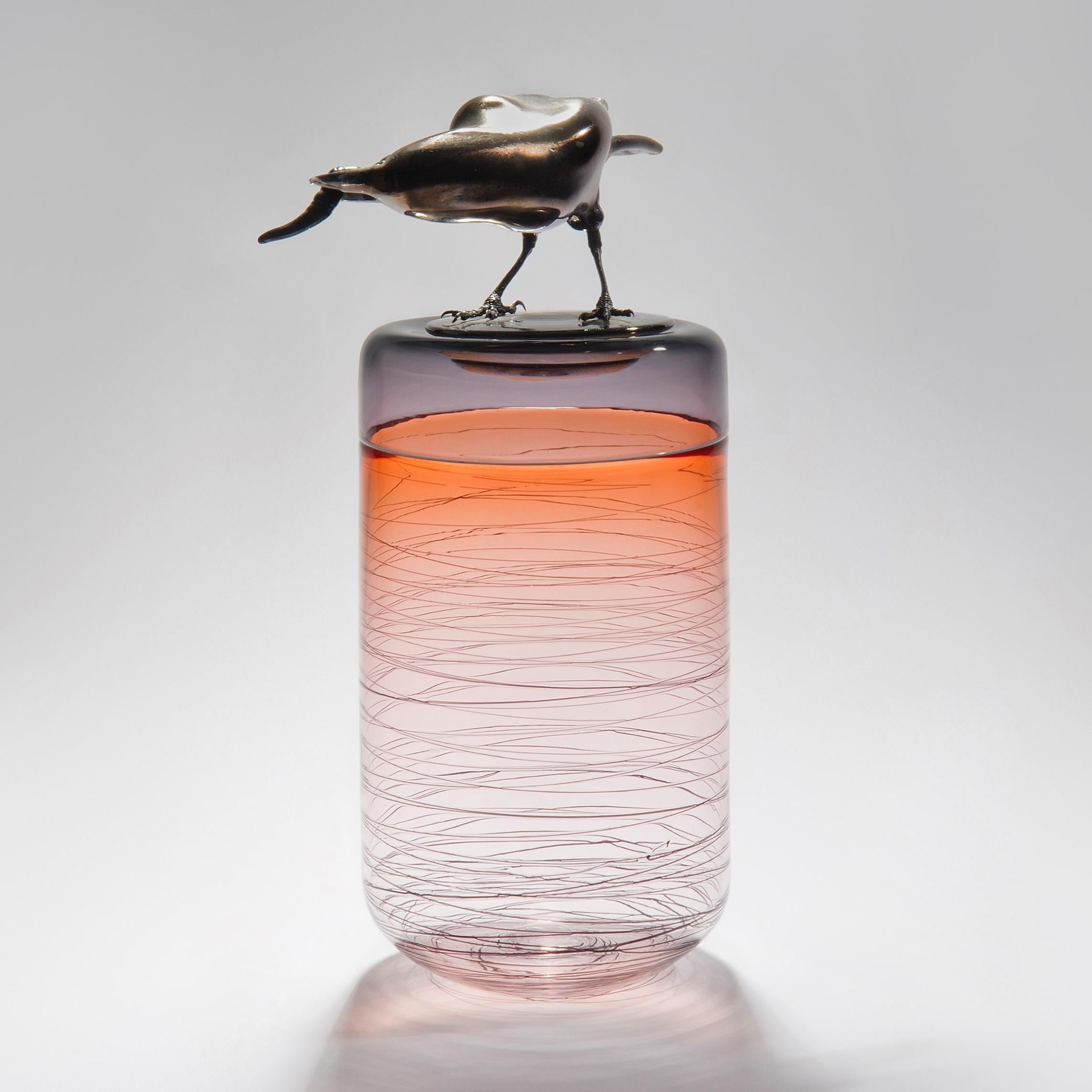 Gourmande, is a hand-blown art glass vase in apricot with a removable lid adorned with a hot sculpted black glass crow holding a worm by the British artist Julie Johnson. The crow figurine can also be lifted off with the main body leaving a