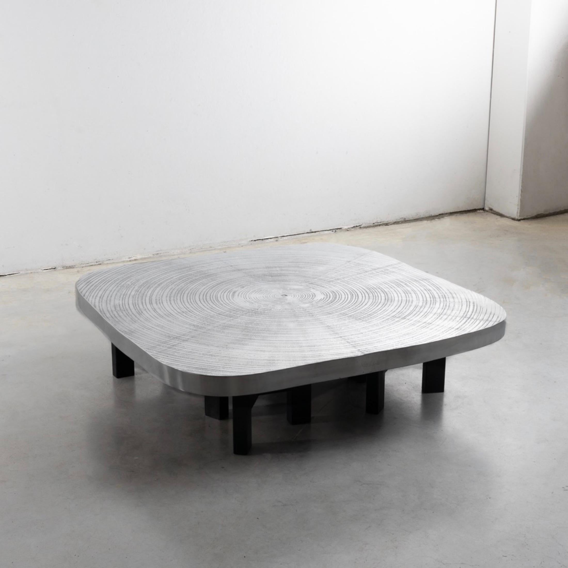 Large square “Goutte d’eau” coffee table with rounded corners.
The top rests on four tripod legs in black painted steel.
The model is named by the artist “Goutte d’eau” because it represents the impact of a drop of water crashing on a surface.
An