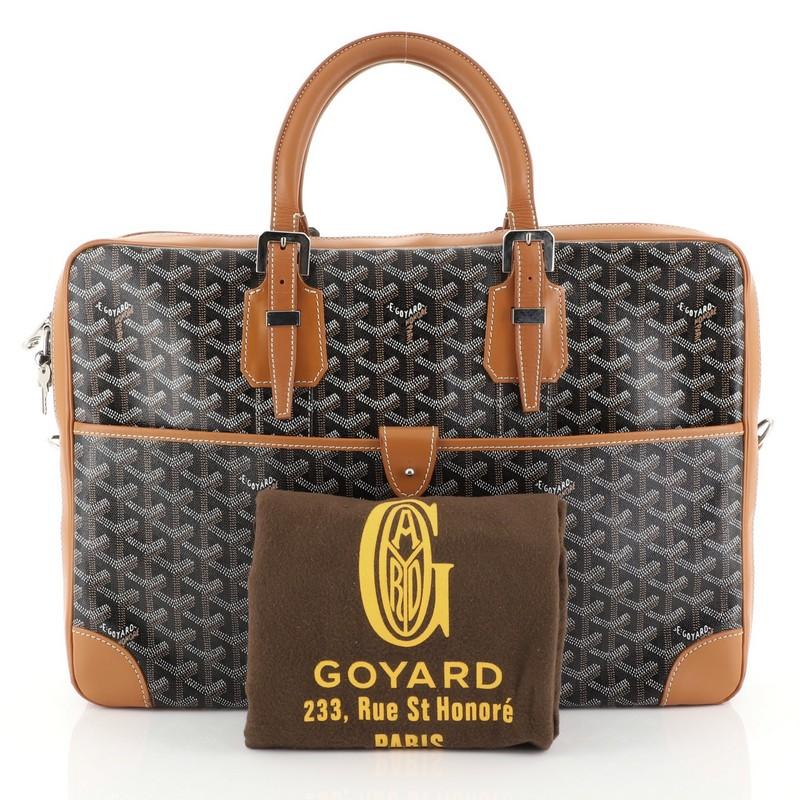 This Goyard Ambassade Briefcase Coated Canvas MM, crafted from brown coated canvas, features dual rolled leather handles with belt details, exterior front pocket, leather trim and silver-tone hardware. Its zip-around closure opens to a yellow fabric