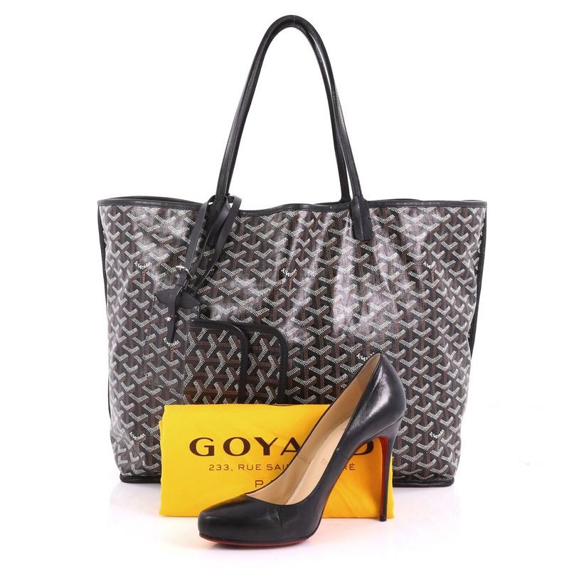 This Goyard Anjou Reversible Tote Coated Canvas GM, crafted in black and brown coated canvas, features dual-flat leather handles, black leather trims, and silver-tone hardware. It wide opens a black leather interior. **Note: Shoe photographed is