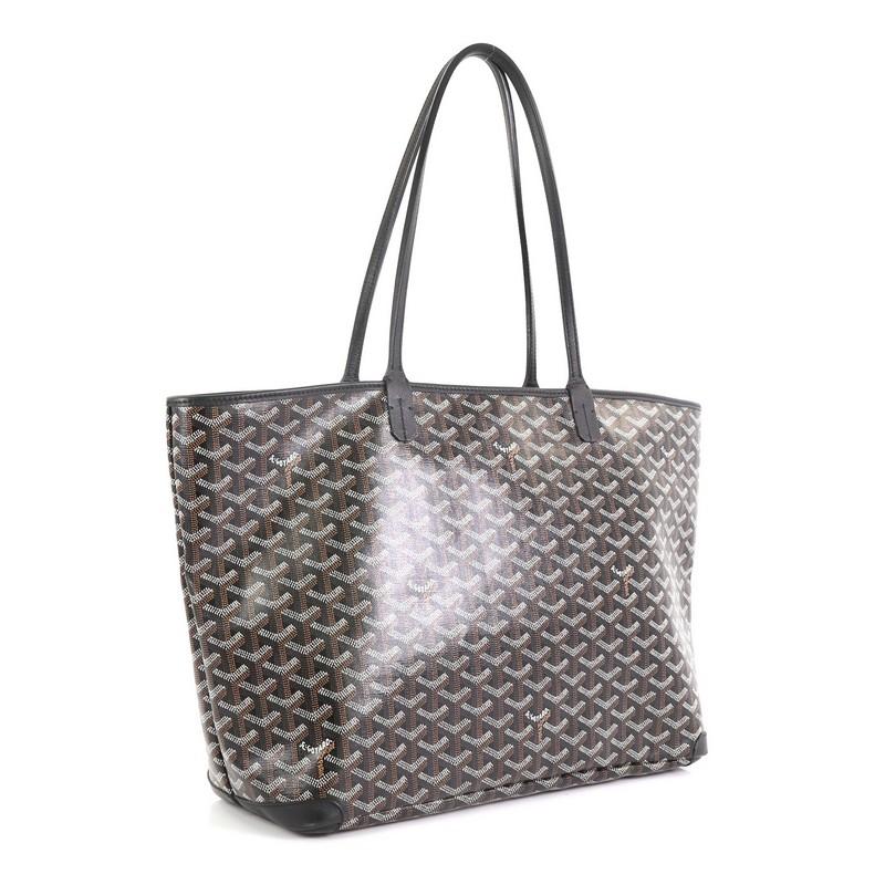 This Goyard Artois Tote Coated Canvas MM, crafted in black coated canvas, features dual slim leather handles, leather trim, protective corner patches, and silver-tone hardware. Its zip closure opens to a neutral fabric interior with a hanging patch