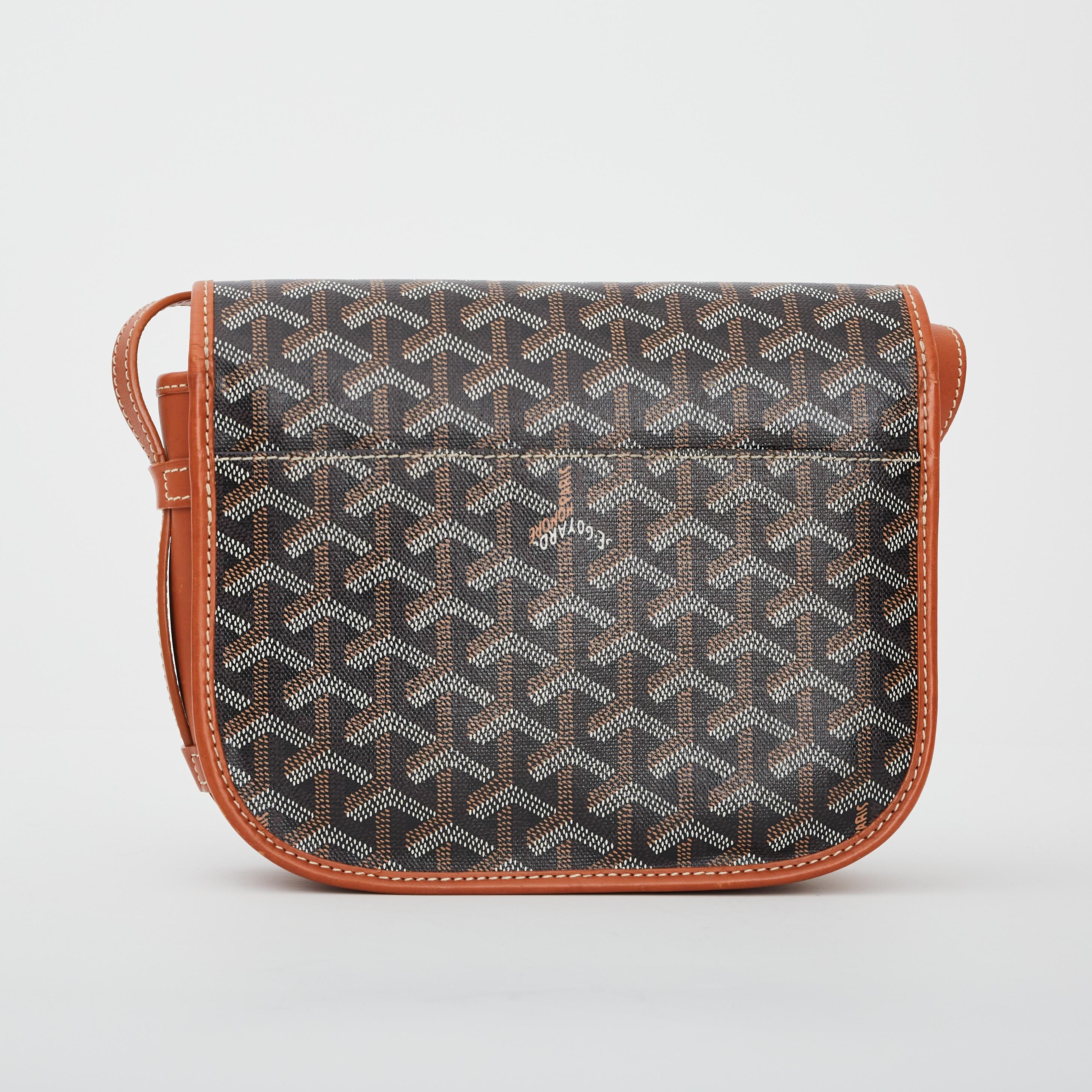 Belvedere MM Bag from Goyard is crafted in signature coated canvas in black featuring tan leather trims and white contrast stitching, an adjustable shoulder strap, front flap with buckle closure and exterior slip pocket at the back. The interior is