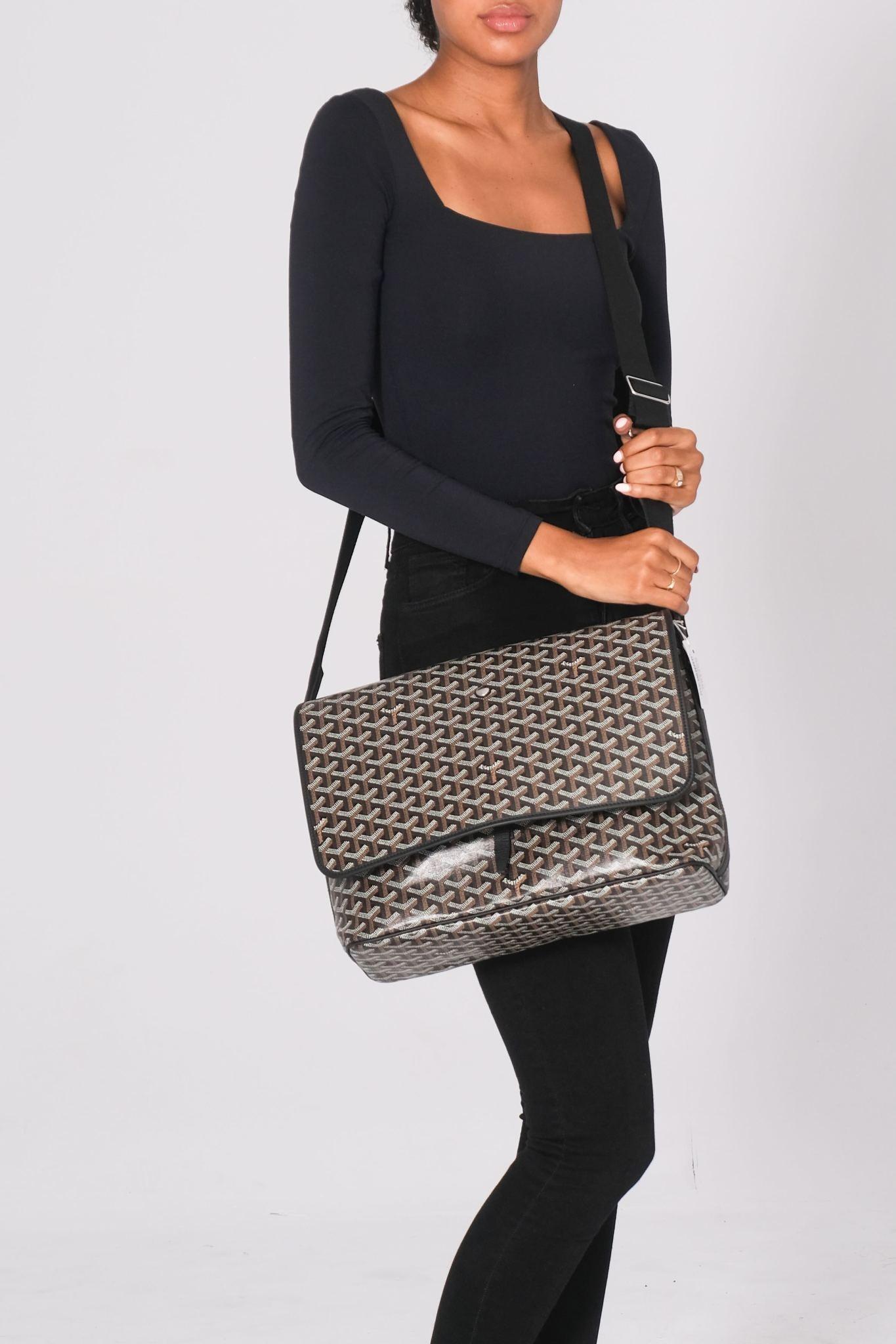 This Goyard Capetien Messenger Bag is constructed of black Goyardine coated canvas with a monogram chevron pattern. It features an adjustable body strap, leather trim, and polished silver hardware. The front flap opens to a fabric interior with