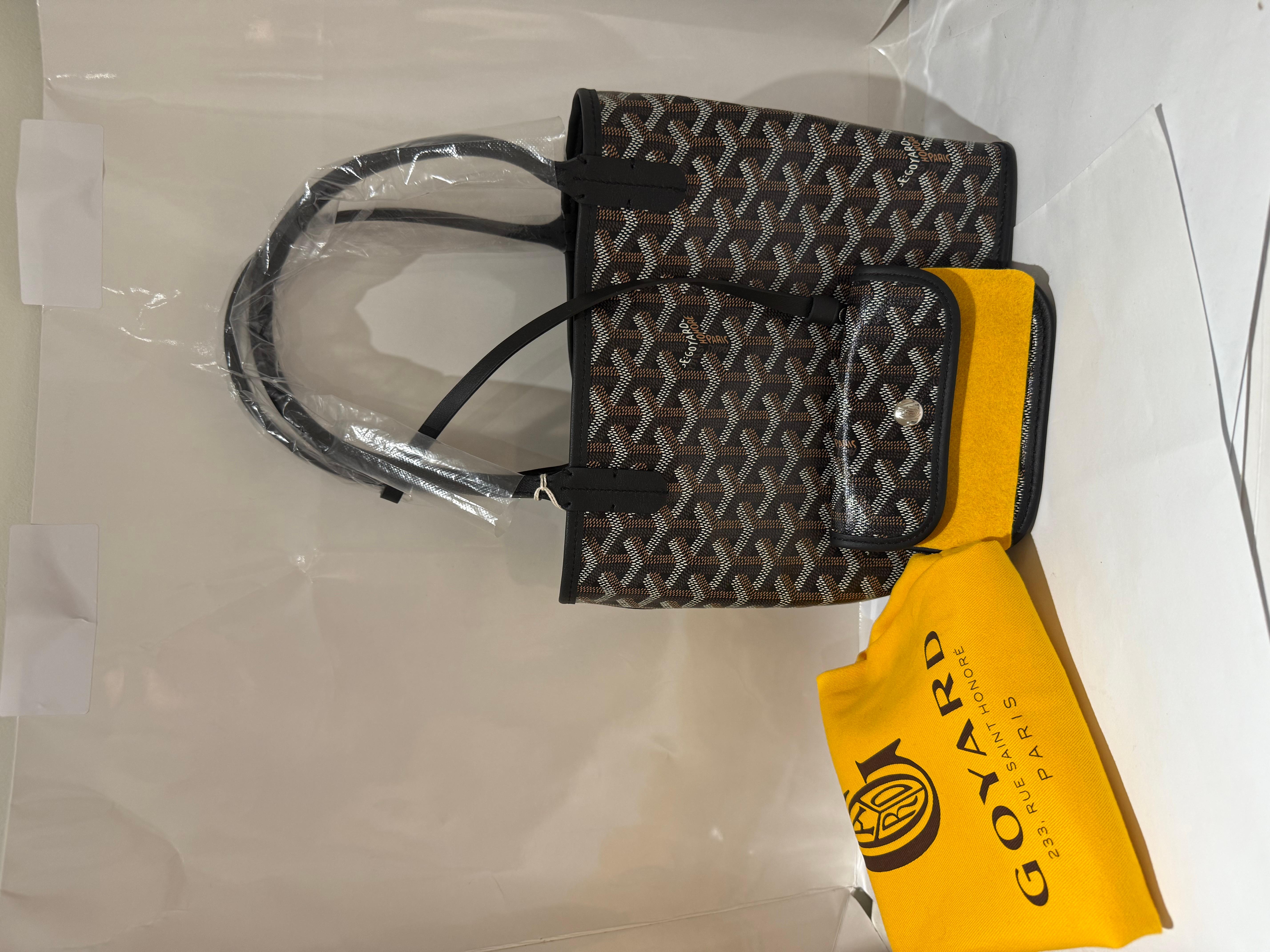 GOYARD BLACK GOYARDINE CANVAS REVERSIBLE MINI ANJOU TOTE. 
The Anjou Mini bag is a nod to our emblematic Saint Louis bag but in a leather version lined with Goyardine. Thanks to its reversibility the Anjou offers two different styles and aesthetics: