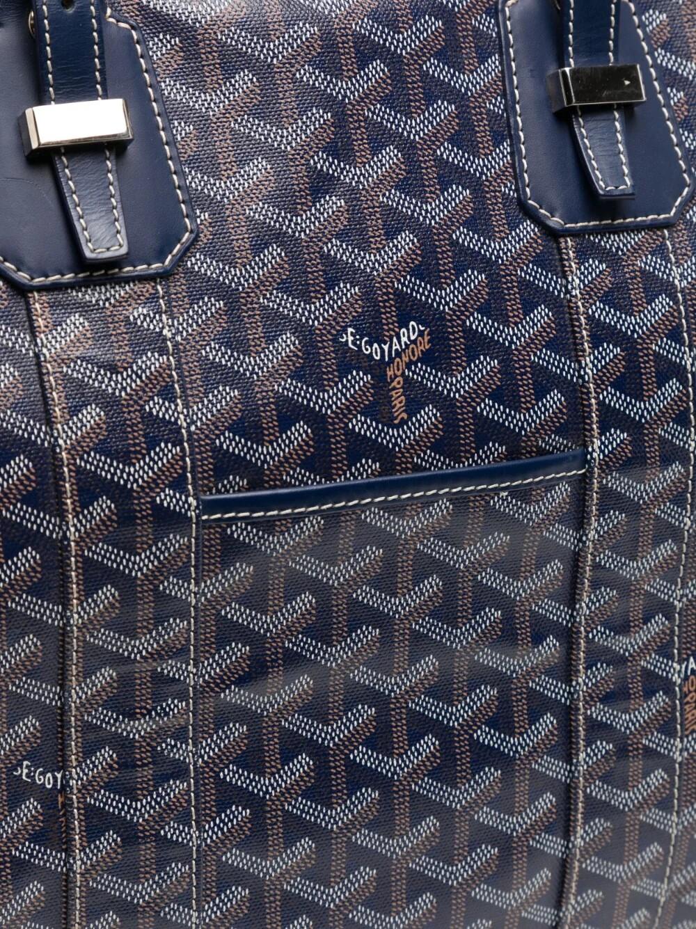 The perfect weekender bag, this holdall travel bag has the iconic Goyard navy monogram all over. It features two adjustable top handles and an adjustable detachable shoulder strap for practical use. With an internal yellow lining, this bag also has
