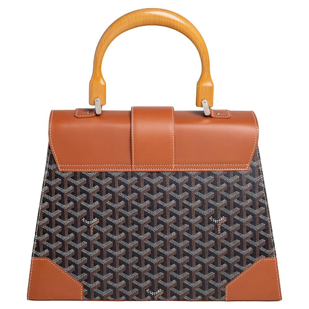 This handbag from Goyard will make the dream of countless women come true. Crafted from the brand's signature Goyardine canvas and leather, this bag has luscious brown and cognac shades, wood trims, and a fold-in lock on the flap. While the shape
