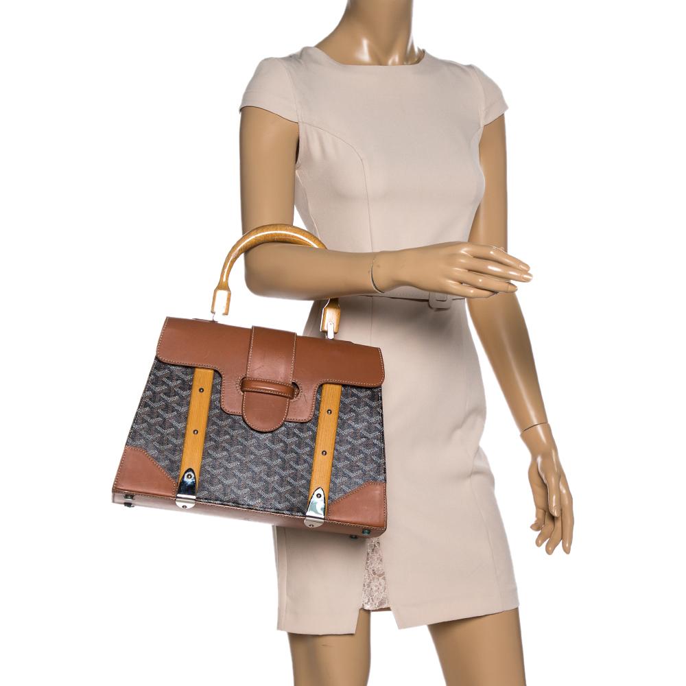 This handbag from Goyard will make the dream of countless women come true. Crafted from the brand's signature coated canvas and leather, this bag has a luscious brown shade, wood trims and a fold-in lock on the flap. While the shape and detailing