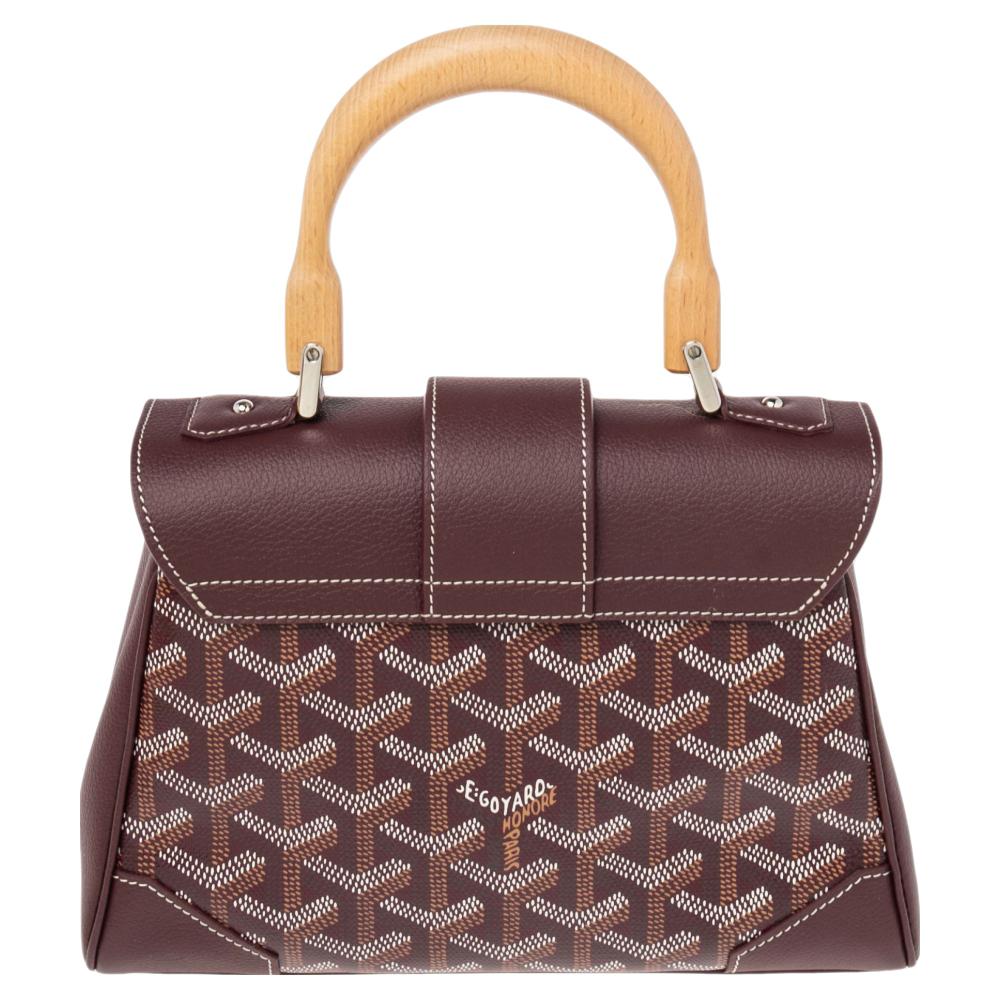 This handbag from Goyard will make the dream of countless women come true. Crafted from the brand's signature Goyardine canvas and leather, this bag has a burgundy shade and a fold-in lock on the flap. While the shape and detailing elevate its