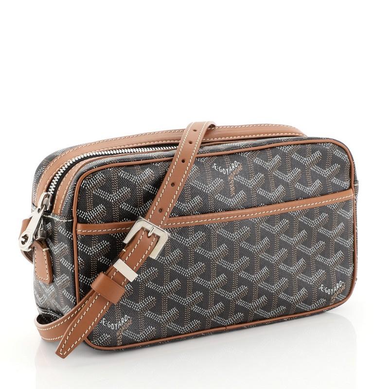 This Goyard Cap Vert Handbag Coated Canvas, crafted from black coated canvas, features a flat adjustable leather shoulder strap, leather trim, exterior front slip pocket, and silver-tone hardware. Its zip closure opens to a yellow fabric interior
