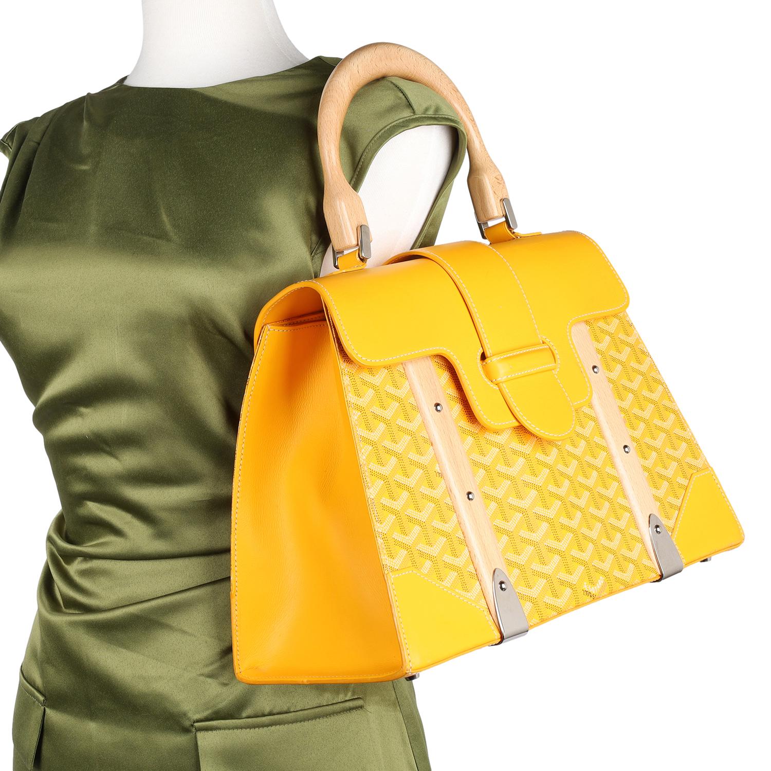 Authentic GOYARD Goyardine Saigon MM tote in Yellow. This stylish travel case or everyday handbag features a yellow coated canvas with the classic Goyard chevron pattern and yellow leather trim, wooden handle, wooden front panels, silver hardware,