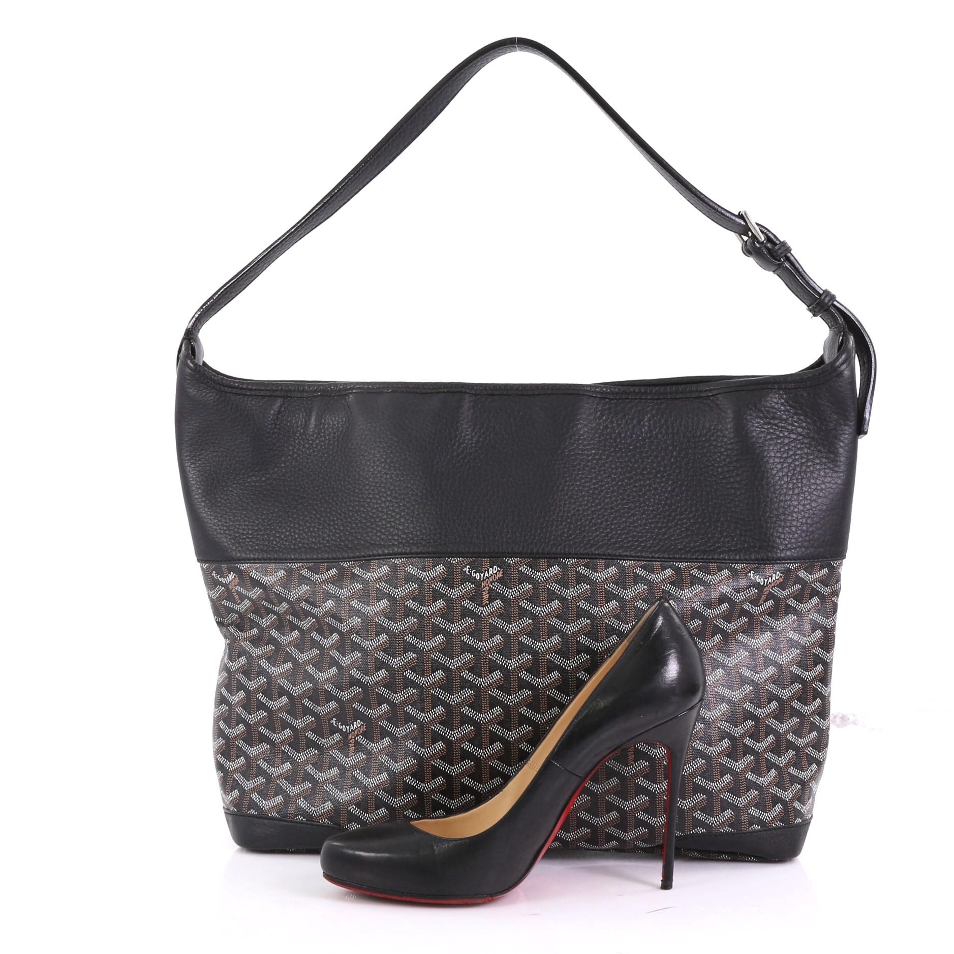 This Goyard Grenadine Hobo Coated Canvas with Leather, crafted from black coated canvas with leather, features an adjustable flat leather shoulder strap, leather trim, and silver-tone hardware. Its zip closure opens to a beige fabric interior.