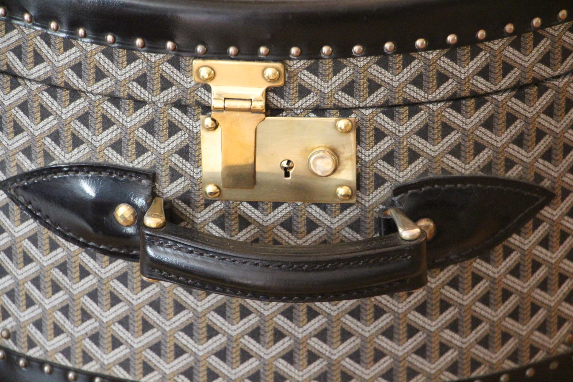 This wonderful Goyard hat trunk features the very sought after chevrons woven canvas as well as brass lock and clasps . Its shape is like a horse shoe. It has got also a beautiful black trim all around. Its large black leather handle is very