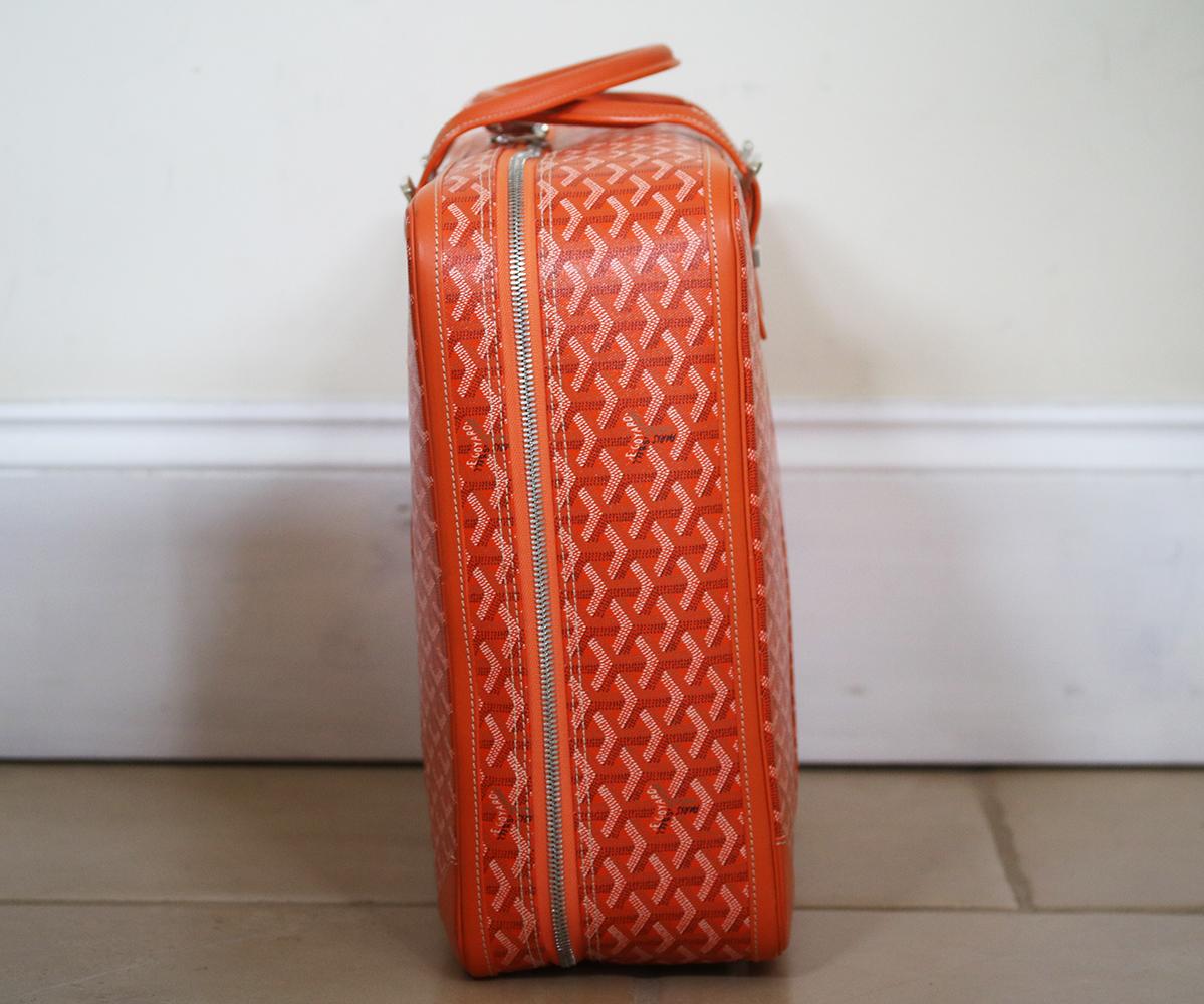 Orange Goyard Majordome 50 suitcase with monogram leather, palladium hardware, rolled handles, canvas lining, two interior pockets; one with zip pocket, leather trim and zip closure at top. Personalised detail on the front. 

Dimensions: 14.5 x 19 x