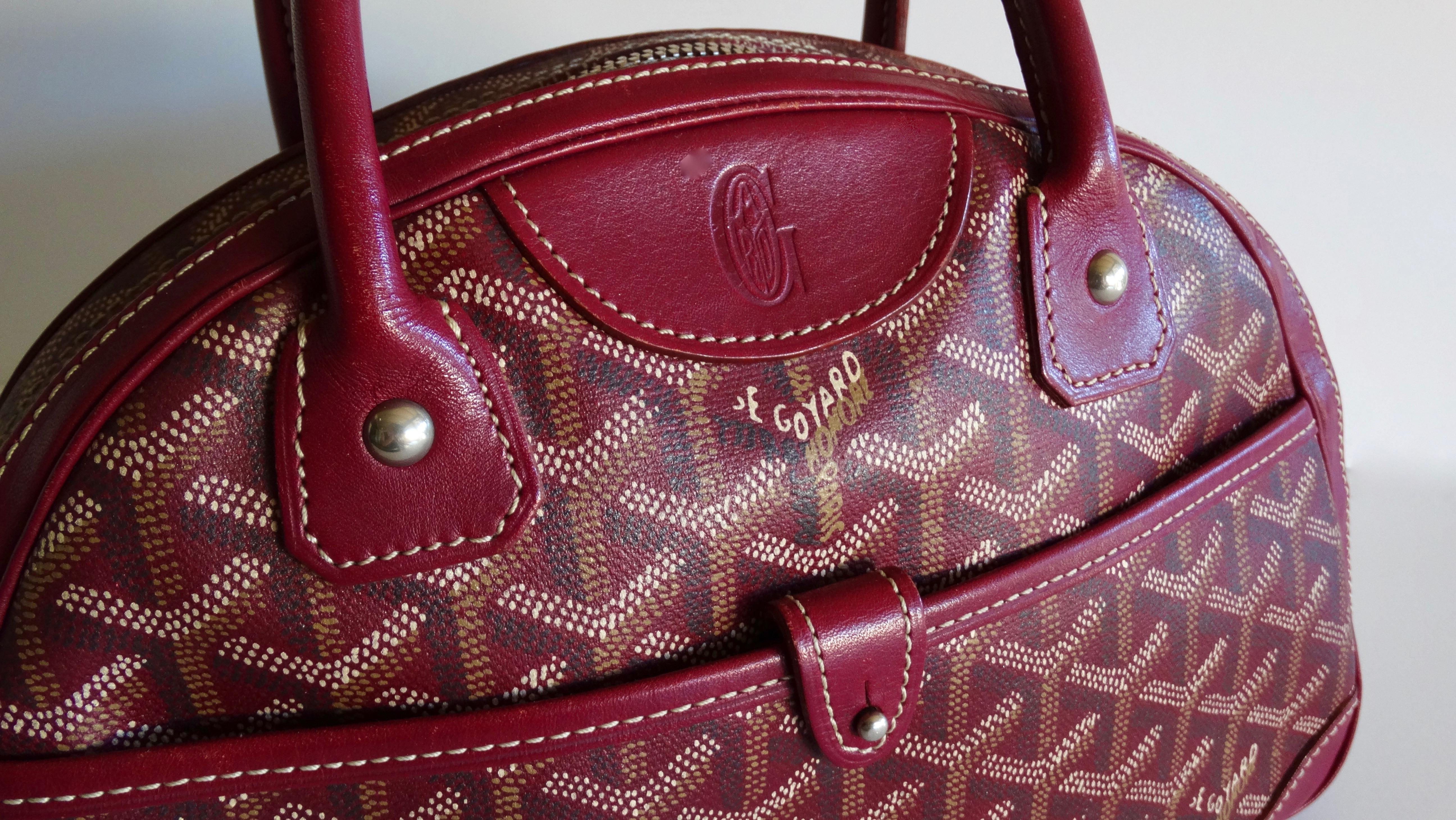 Snag yourself the bag of your dreams with this adorable Goyard! Circa 1990s, this St. Jeanne PM bowling bag is made from Burgandy canvas and features the iconic Goyard monogram. Includes a snap button front face pocket, rolled leather dual top