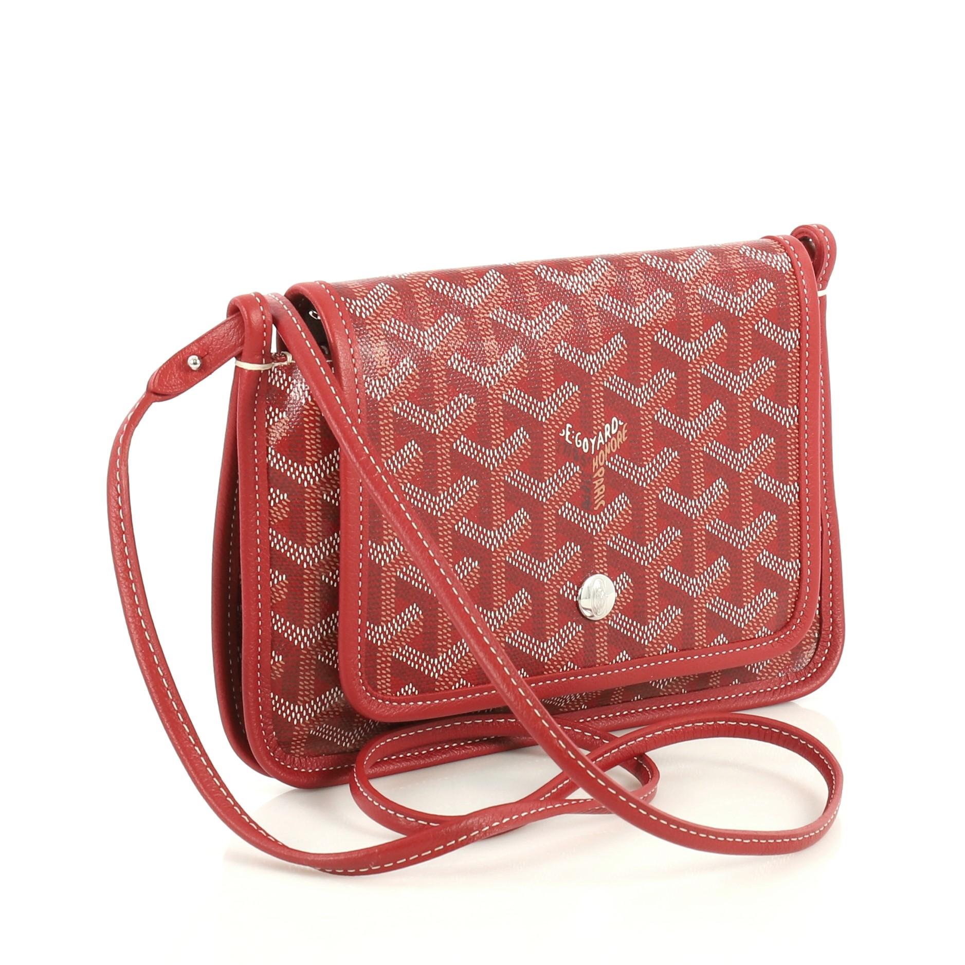 This Goyard Plumet Clutch Wallet Coated Canvas, crafted from red coated canvas, features a detachable leather strap, leather trim and silver-tone hardware. Its snap closure opens to a neutral fabric interior with zip pocket. 

Condition: Pristine.