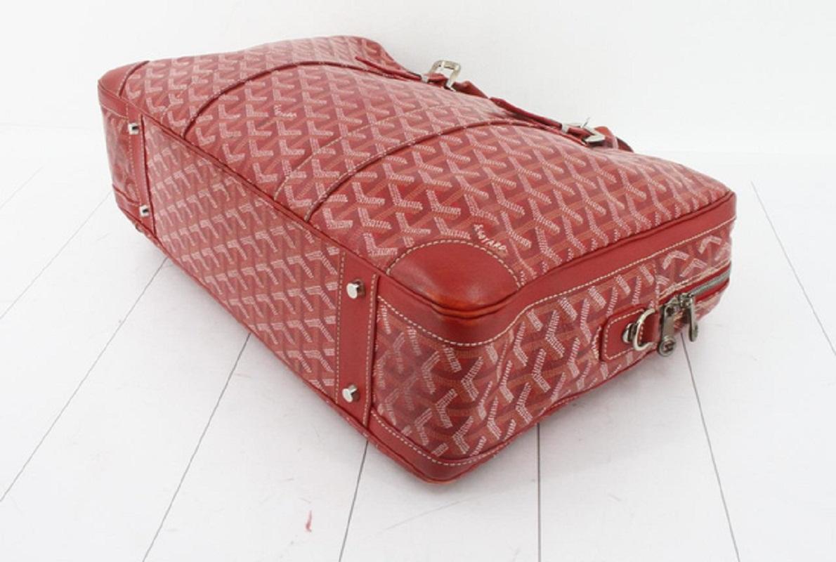 Red Goyardine Chevron monogram Goyard Ambassade MM briefcase features dual rolled leather top handles with silver-tone buckles, a facing patch pocket, and leather trim. The wrap around zipper opens to a mango yellow fabric interior with pockets.

