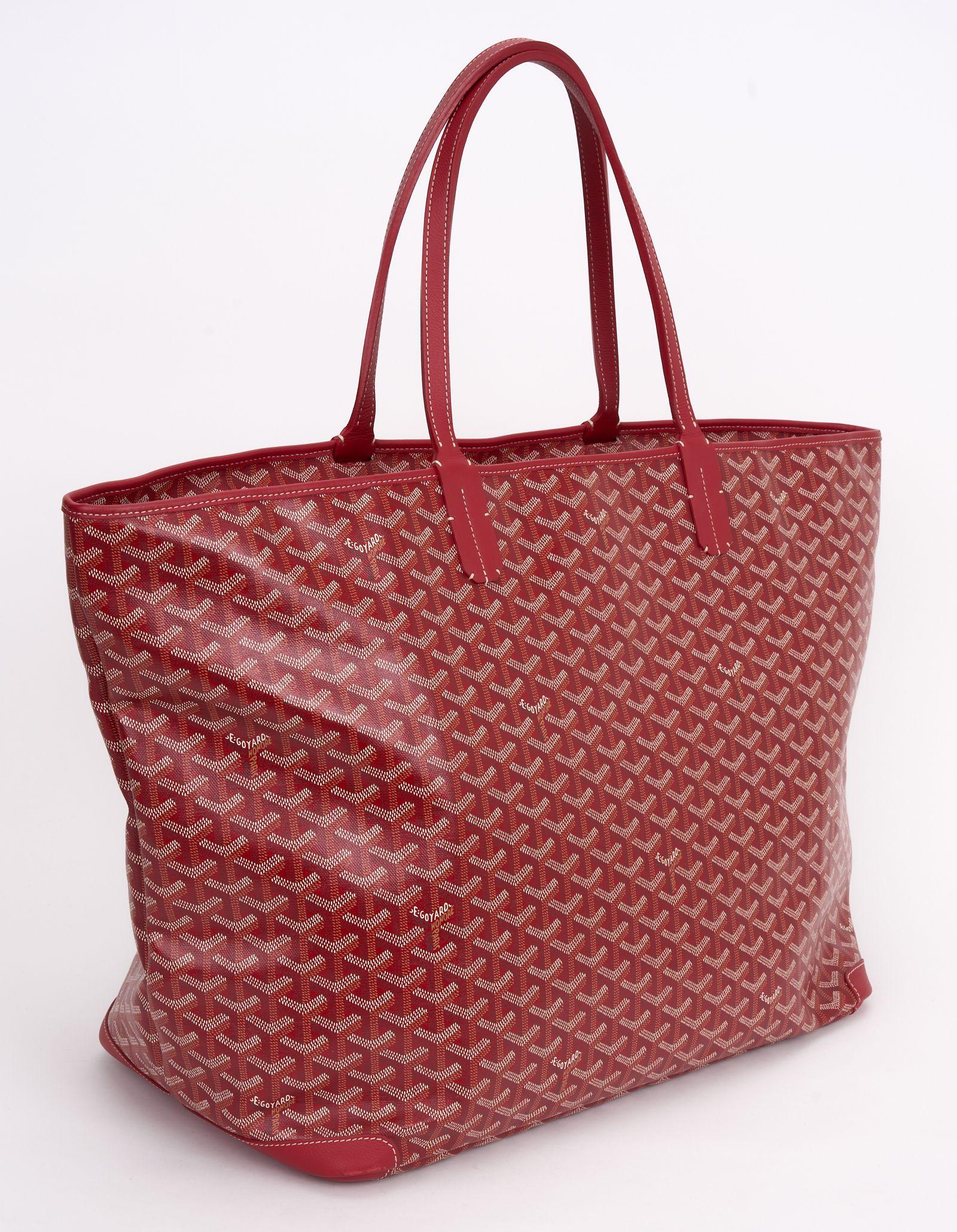 This Goyard, Goyardine Saint Louis tote features signature Goyard chevron printed coated canvas in red. The shoulder bag features sturdy red leather strap handles and matching leather trim. The top is open to a spacious ivory canvas interior with a