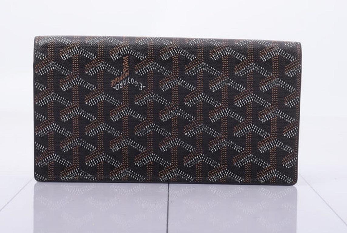Goyard Richelieu long wallet is crafted of classic Goyardine Chevron coated canvas in black. The wallet opens in a folder style to a compact smooth black leather interior with card slots, patch pockets and a zipper yellow canvas-lined