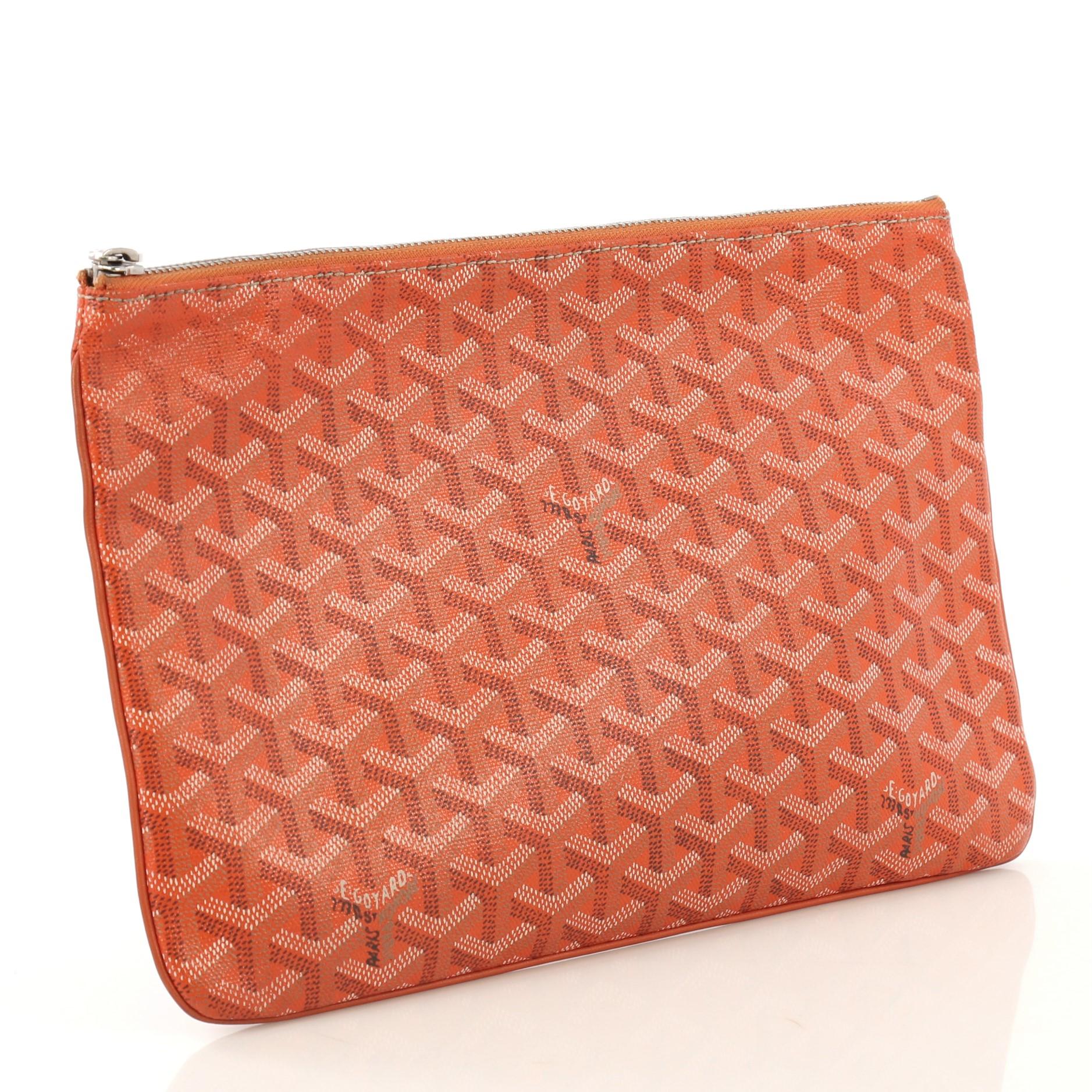This Goyard Senat Zip Pouch Coated Canvas MM, crafted from orange coated canvas, features silver-tone hardware. Its zip closure opens to a yellow fabric interior with slip pocket. 

Estimated Retail Price: $1,145
Condition: Very good. Wear and