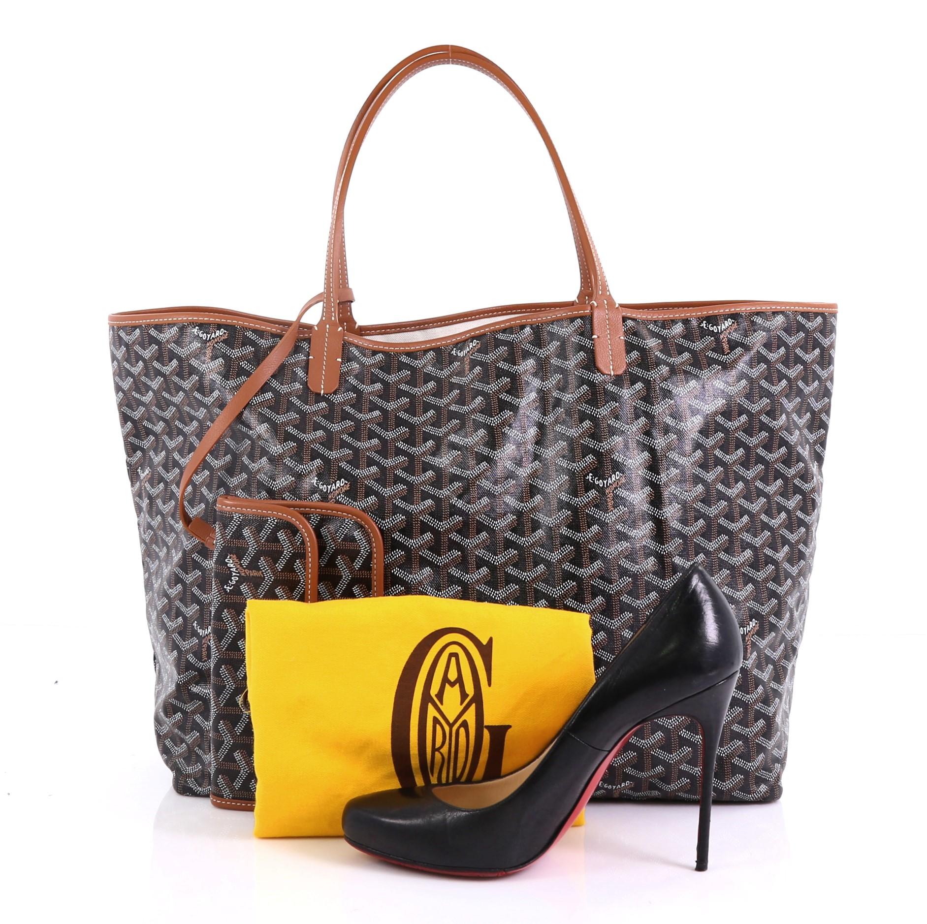 This Goyard St. Louis Tote Coated Canvas GM, crafted in black coated canvas and brown leather, features flat leather handles and silver-tone hardware. Its wide open top showcases a beige fabric interior. **Note: Shoe photographed is used as a sizing