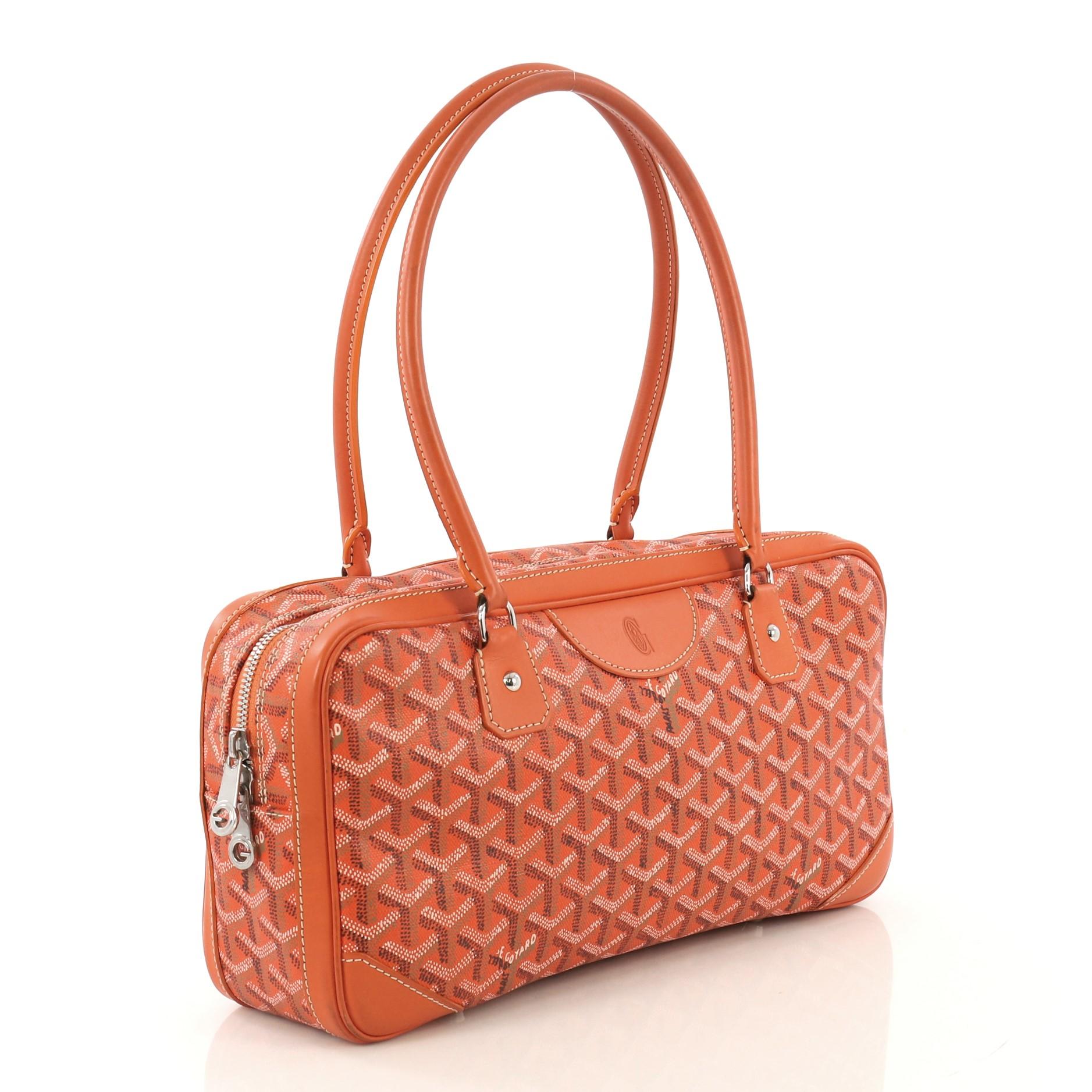 This Goyard St. Martin Handbag Coated Canvas, crafted from orange coated canvas, features dual rolled leather handles, leather trim, exterior front flap pocket, protective base studs, and silver-tone hardware. Its two-way zip closure opens to a