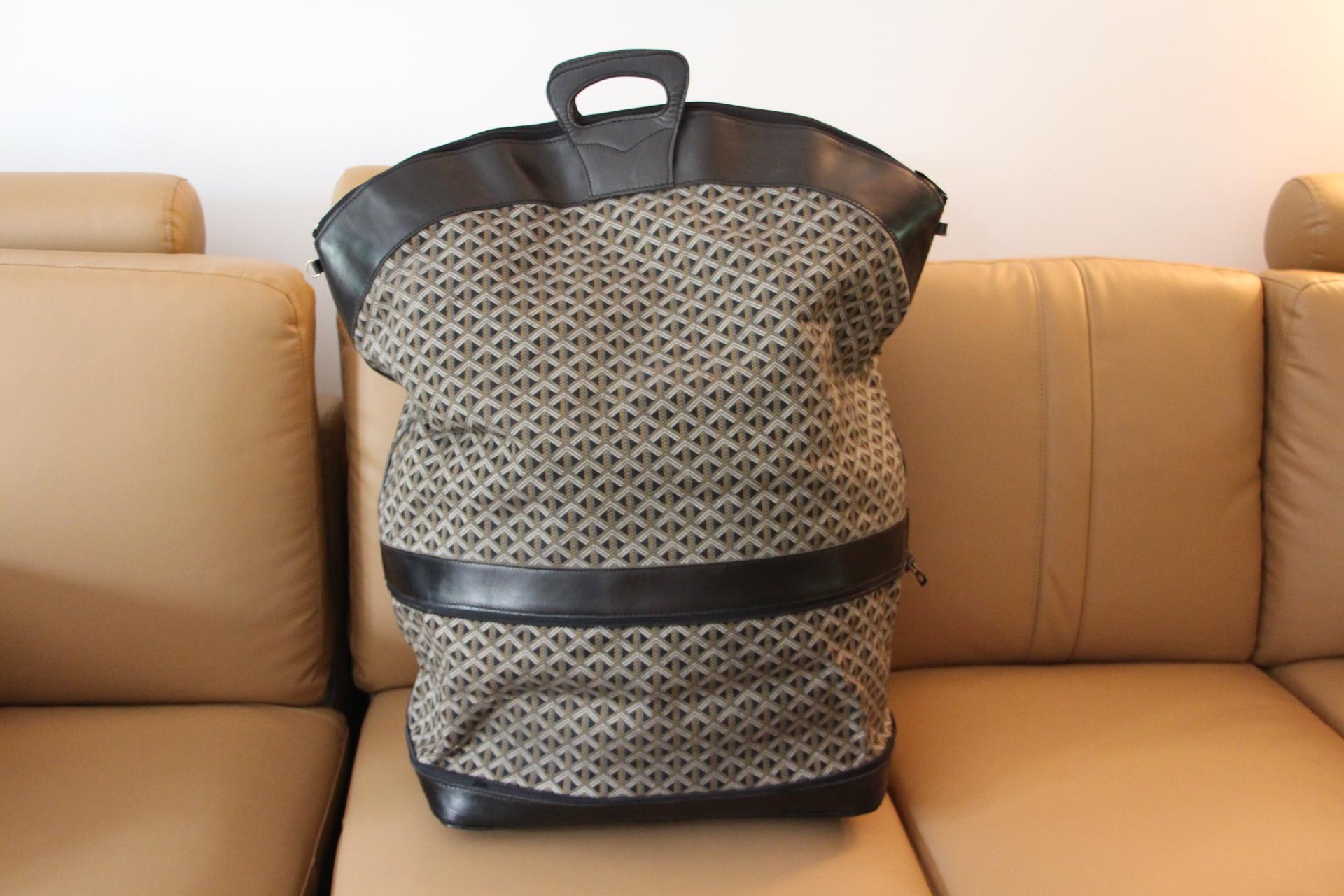 An oversized vintage Goyard travel bag in black leather and woven chevrons canvas with a yellow colored canvas interior.
Its two large leather handles are very sturdy and very comfortable.All its bottom section is black leather.
At the end of the