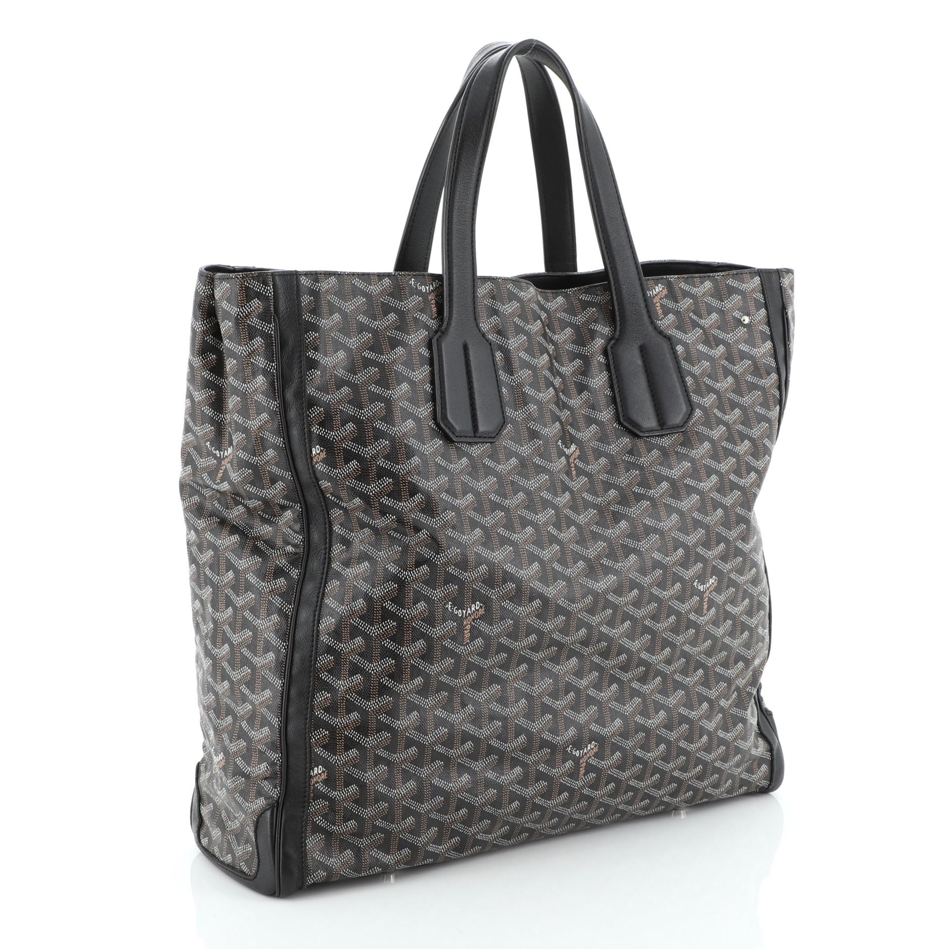 This Goyard Voltaire Convertible Tote Coated Canvas, crafted from black coated canvas, features dual flat handles, protective base studs, and silver-tone hardware. Its open top with middle hook closure opens to a yellow fabric interior with slip