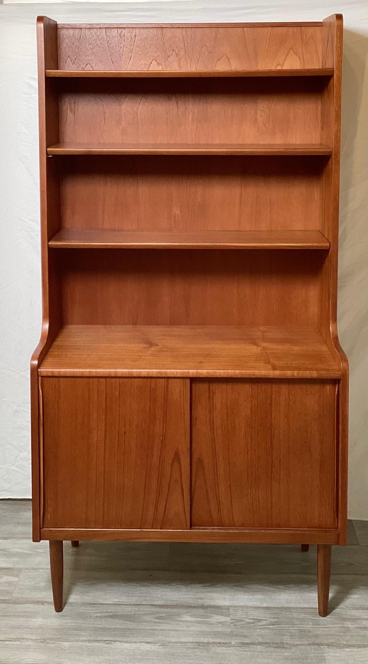 Handsome Danish teak bookcase with 2 shelves and 2 sliding doors for concealed storage.  Practical size that can be used in many settings.  Great condition and ready to beautify your home.