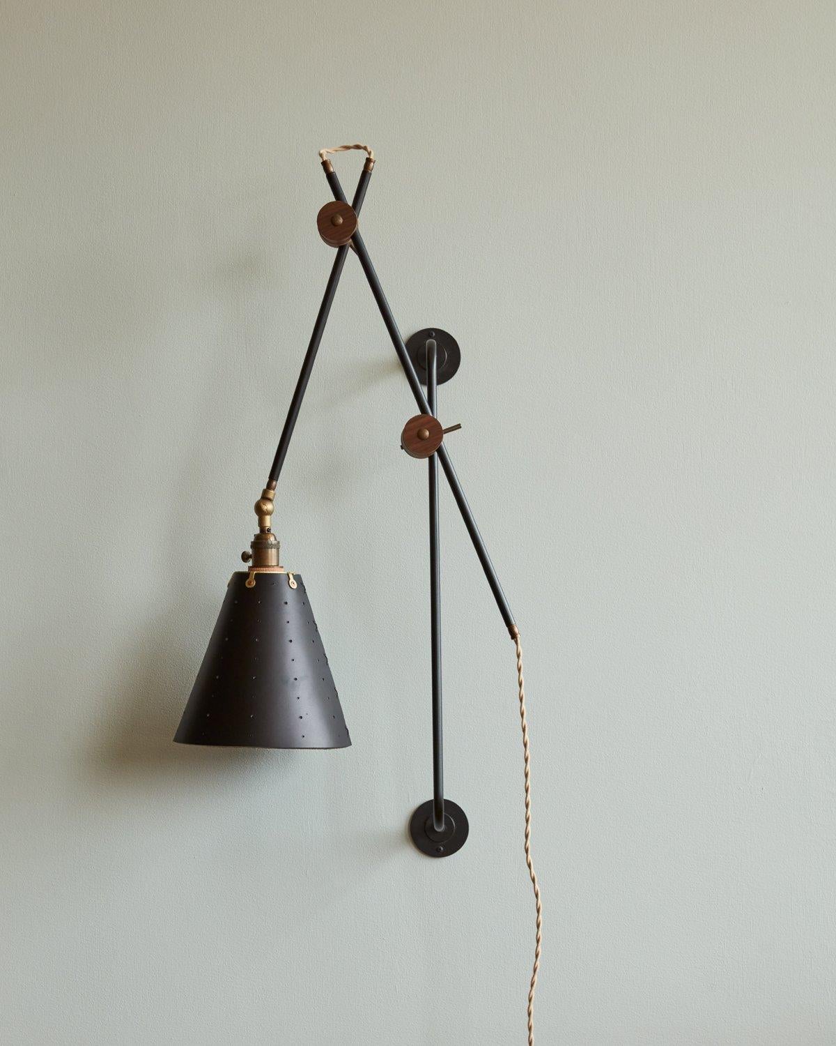 Celebrated for its striking composition and versatility, the Grace Articulating Wall Sconce is a true hallmark of ingenuity in lighting design. As handsome as it is useful, this plug-in sconce connects two lengths of steel piping with a black walnut