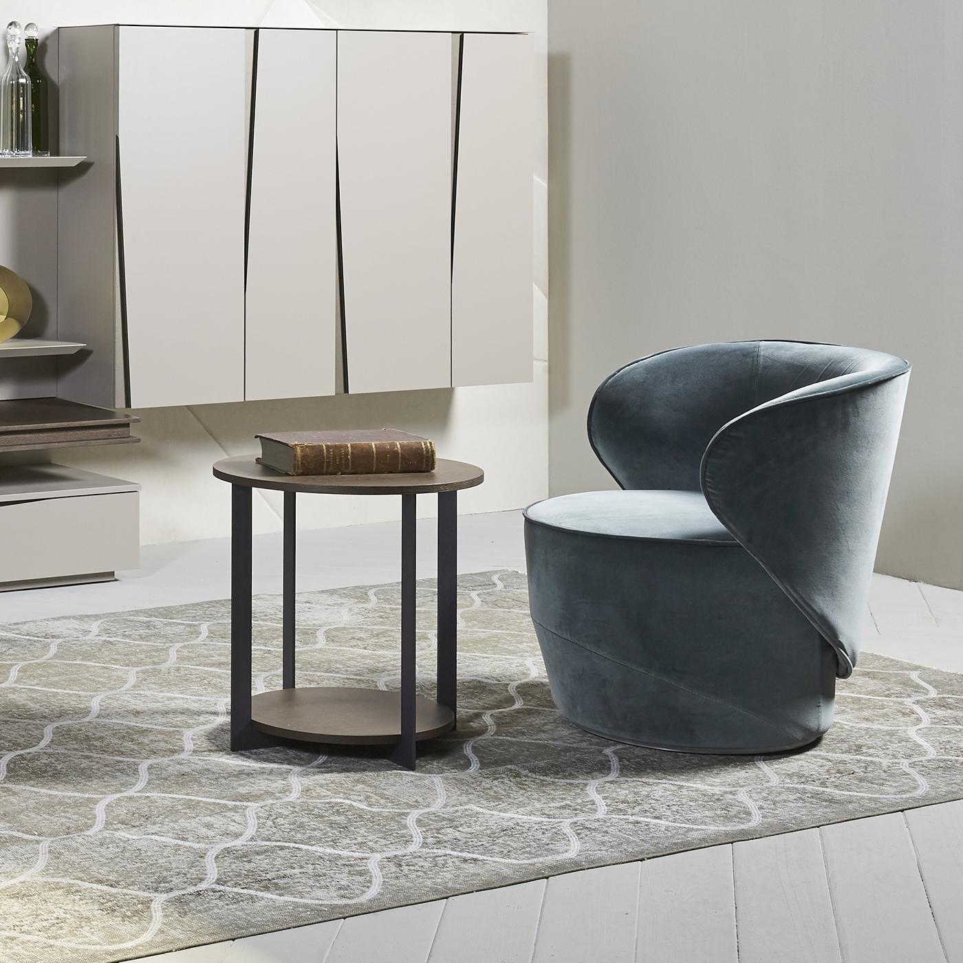 Unique and elegant, this swivel armchair boasts a round base enveloped by the armrest and back, that create a warm embrace enhanced by the velvet upholstery in peacock blue. This versatile piece will infuse comfort and sophistication in a modern