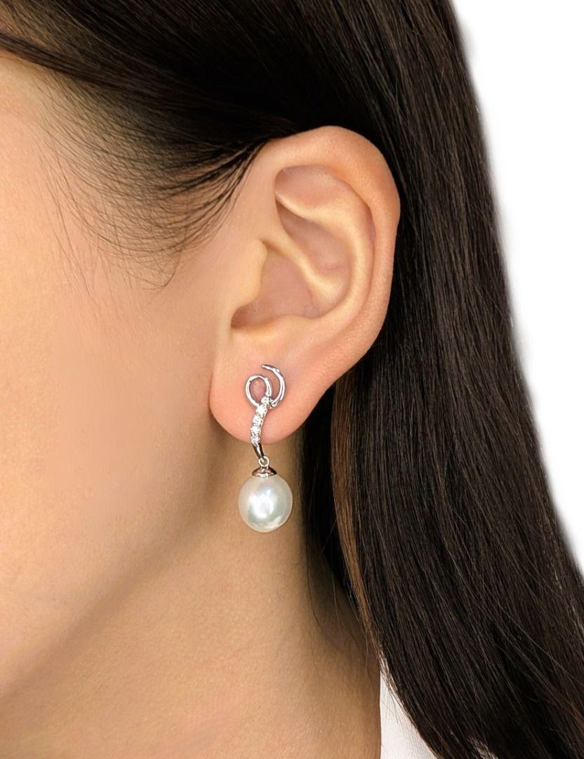 A refined expression of grace and sophistication, these drop earrings are expertly crafted in 18K white gold, featuring two oval-shaped freshwater pearls, each 10.1mm, radiating a soft, luminous glow. Enhancing their beauty, 10 round brilliant-cut