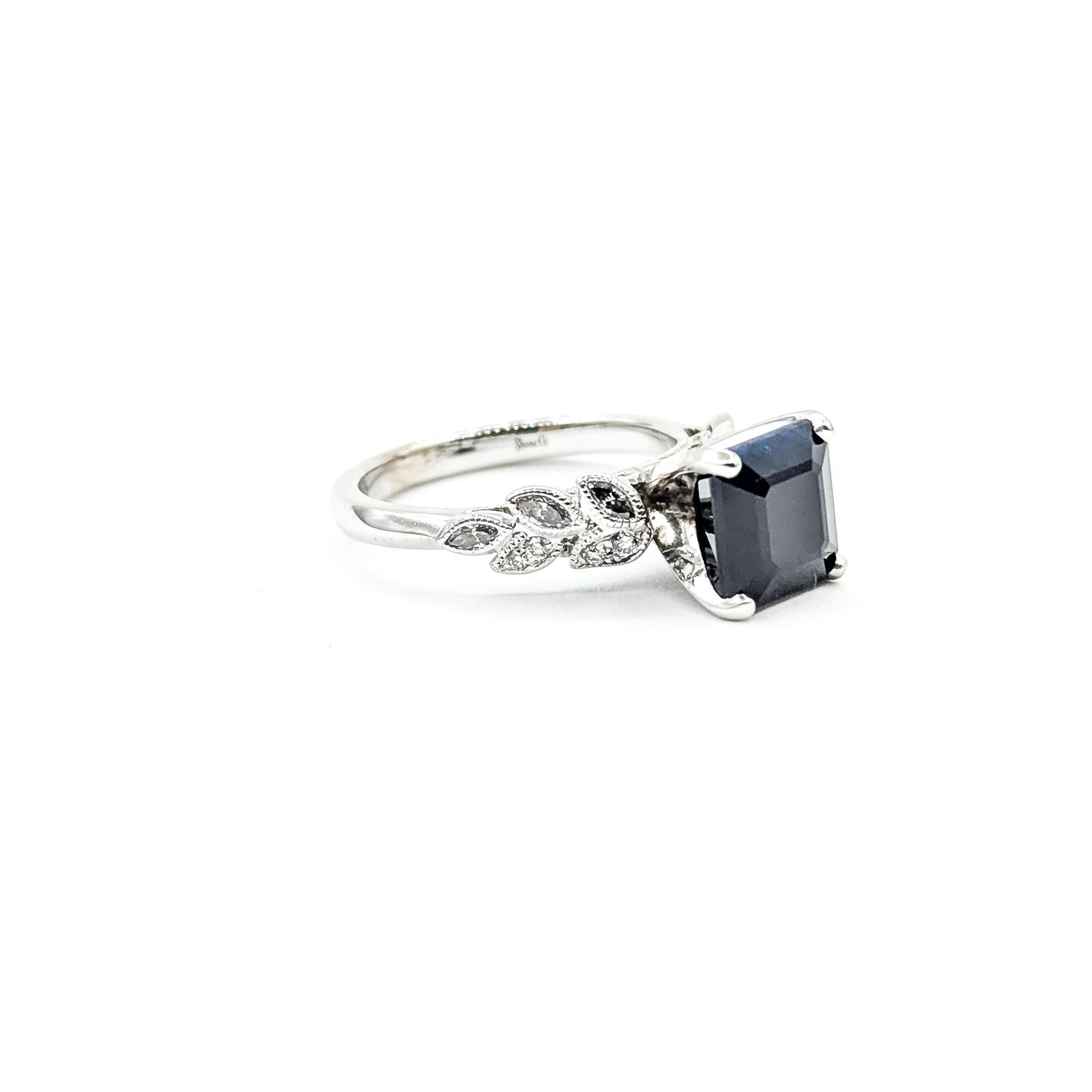 Elegante Anillo Milgrain de Zafiro Negro y Diamantes en Oro Blanco de 14k

Este anillo de compromiso está elaborado en oro blanco de 14 quilates y tiene como piedra central un zafiro negro de 2,75 quilates. El zafiro está engastado en una montura