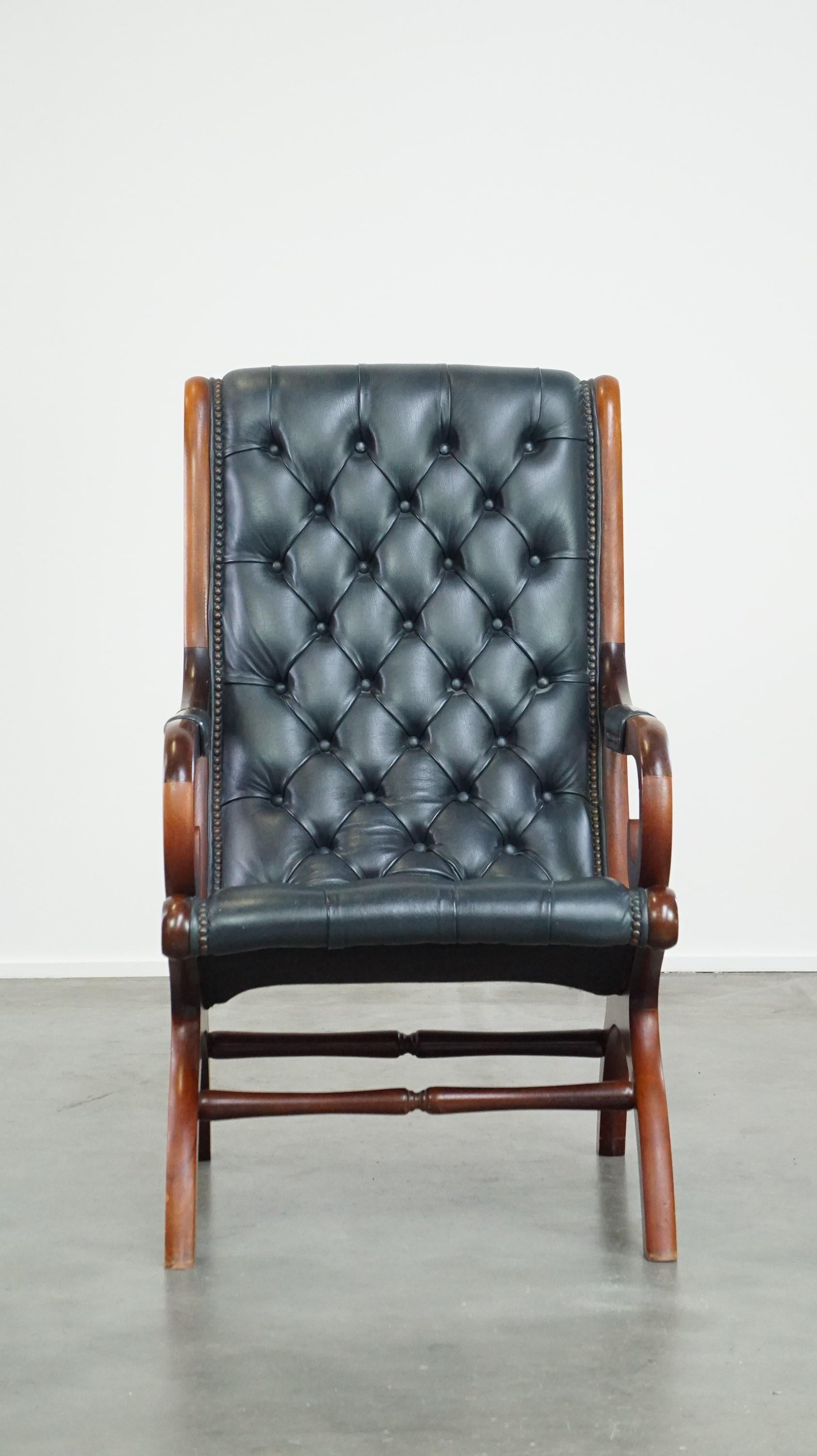 The design, the finish with decorative nails, and the dark blue color make this leather chesterfield armchair a true eye-catcher. Its organic shape provides excellent seating comfort. Due to years of responsible use, it has developed some normal