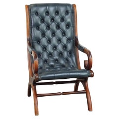 Graceful dark blue chesterfield armchair made of cow leather combined with wood