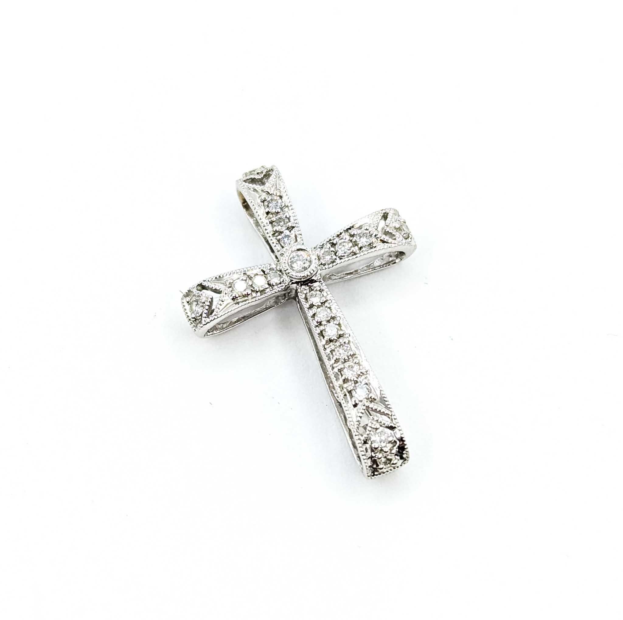 Questo pendente finemente realizzato in oro bianco 18 carati presenta diamanti scintillanti per un totale di 0,12 carati, delicatamente incastonati lungo i bracci della croce. Il design è impreziosito da accenti di grana e dettagli traforati, che