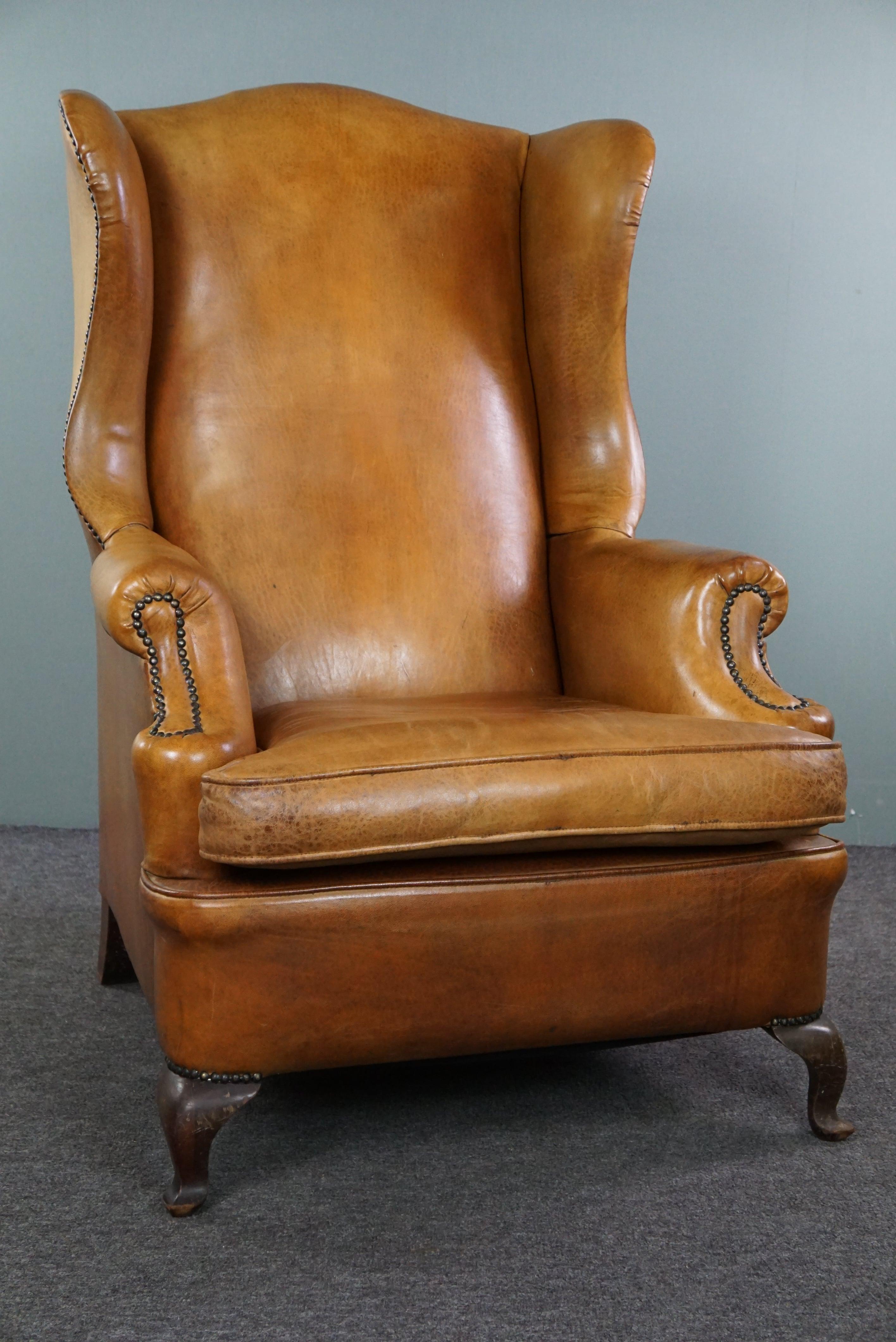 Offered is this graceful old wing chair made of sheep leather in correct condition, finished with decorative nails and Queen Anne legs.

This armchair is a beautiful example of an elegant chair made of sheep leather. There are some minimal signs of