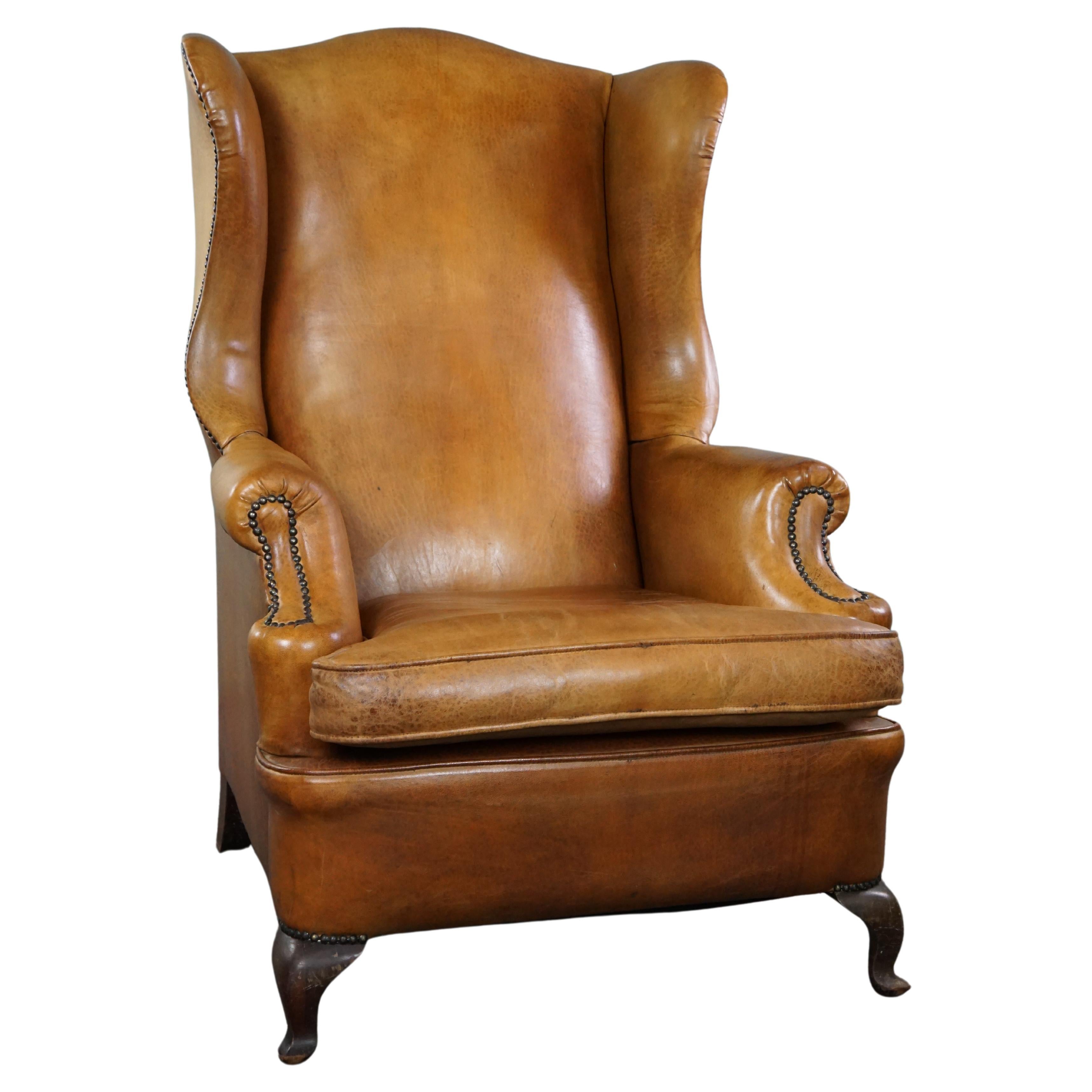Graceful old wing chair made of sheep leather in correct condition For Sale