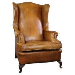 Graceful old wing chair made of sheep leather in correct condition