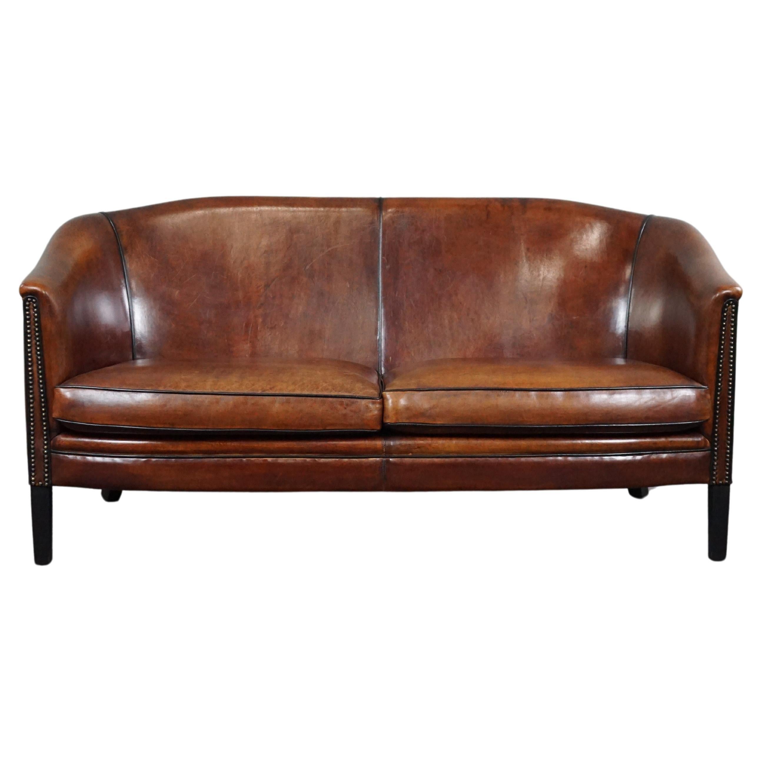 Gracefully shaped sheep leather sofa finished with black piping, spacious 2 seat