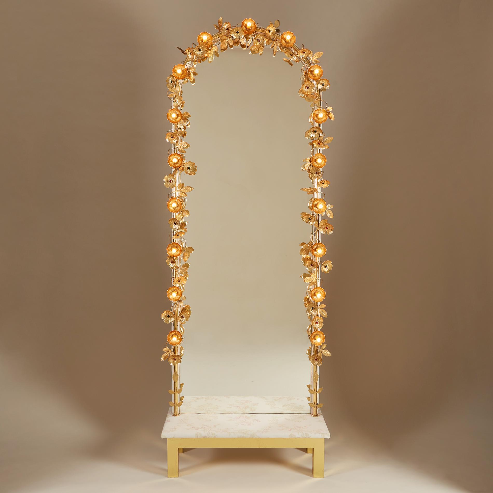 Freestanding mirror with flower lights. Delicate gold brass flowers and leaves encircle our dramatic freestanding light mirror. Each flower is finished with a ruby or emerald centre unless it holds one of seventeen subtle light-up flowers. This