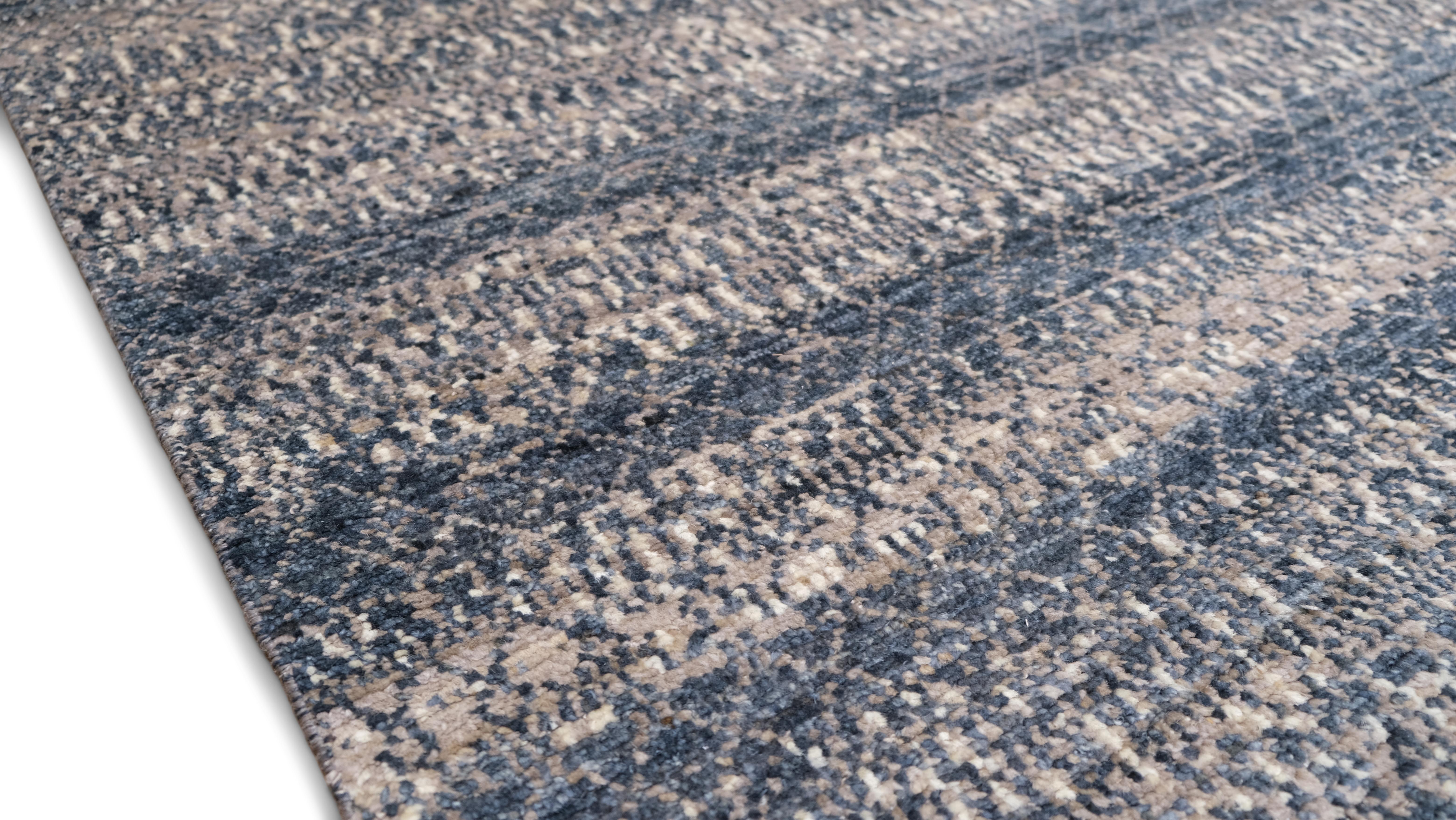 Ce tapis en laine noué à la main incarne l'élégance contemporaine avec une palette de couleurs apaisantes et une texture dégradée raffinée. Avec ses teintes apaisantes de bleus doux, de gris et ses accents subtils d'ivoire, le design crée une