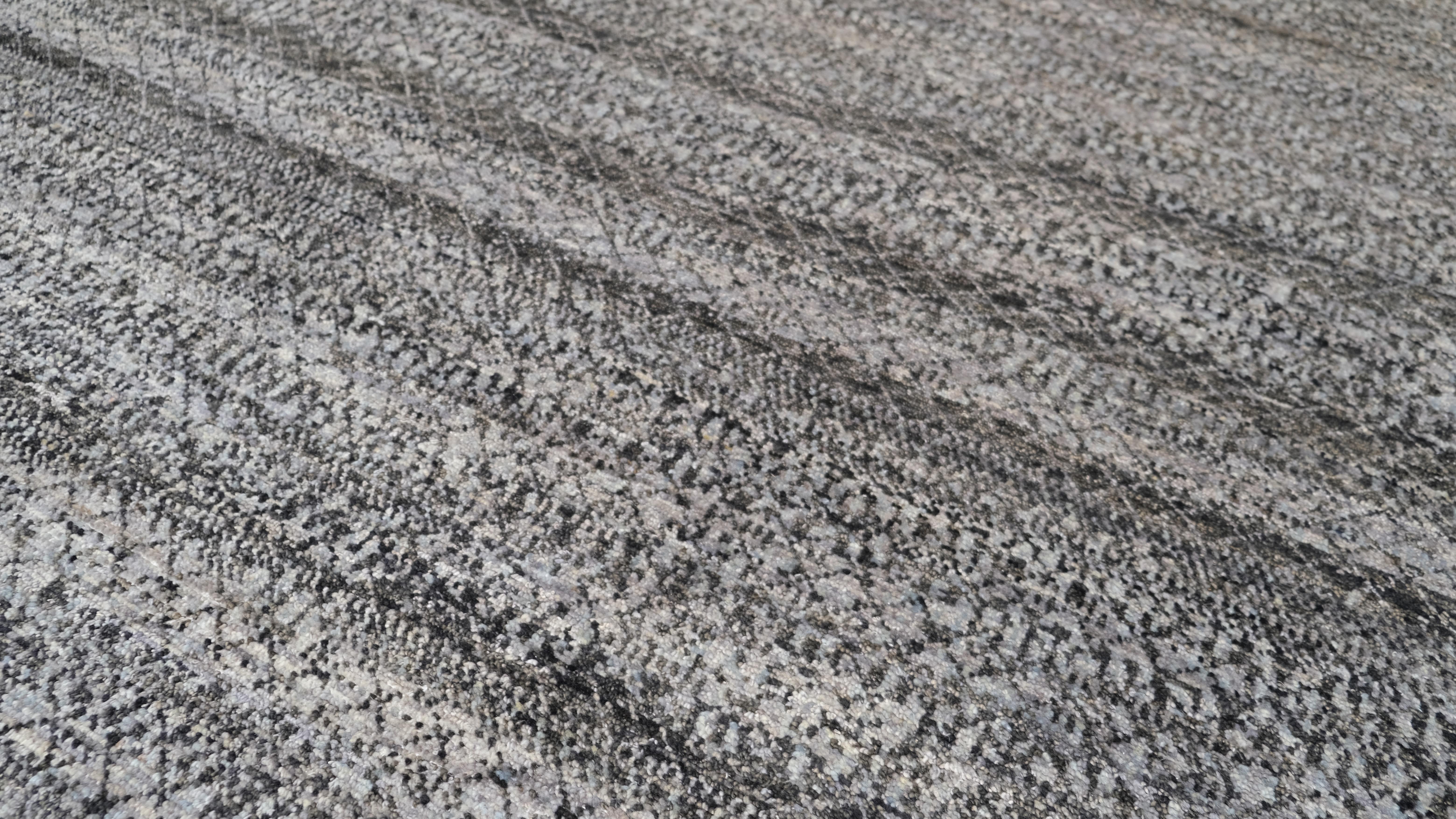 This hand-knotted wool rug is a stunning example of modern craftsmanship combined with timeless appeal. Showcasing a beautifully textured pattern with a subtle gradient effect, the rug features a sophisticated palette of grey, and charcoal tones,