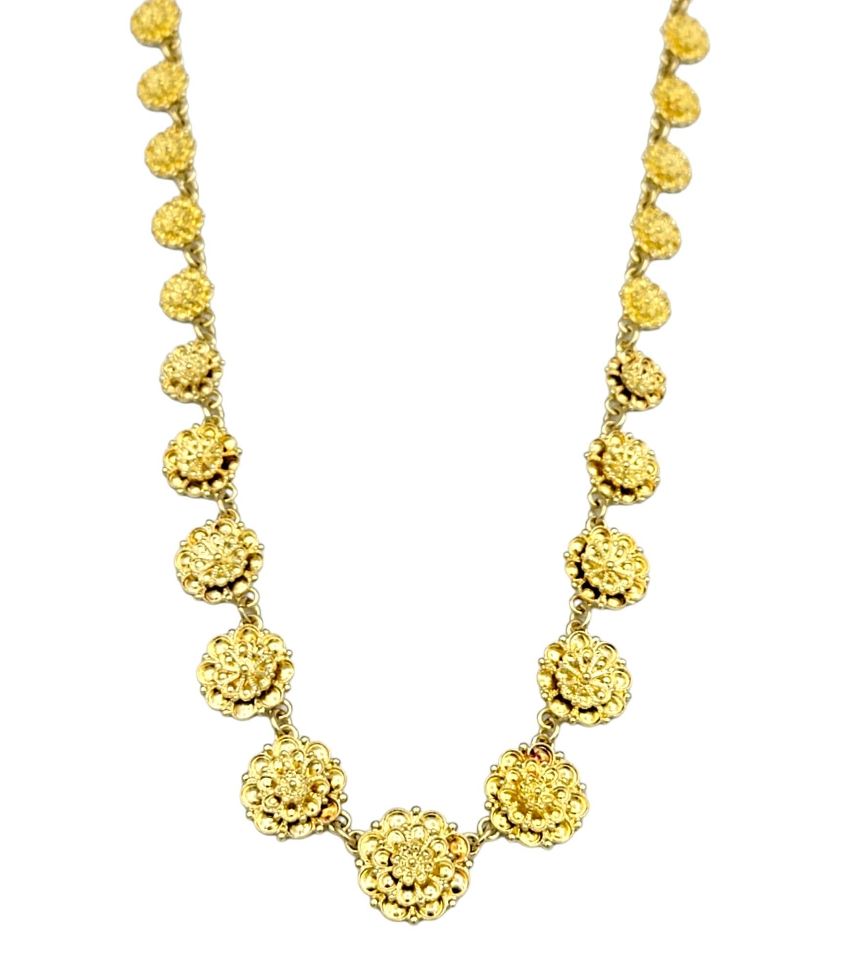 This textured link necklace, crafted in radiant 18 karat yellow gold, is a stunning testament to elegance and refinement. Each link of the necklace features a meticulously detailed flower design, exuding a sense of timeless beauty and femininity.