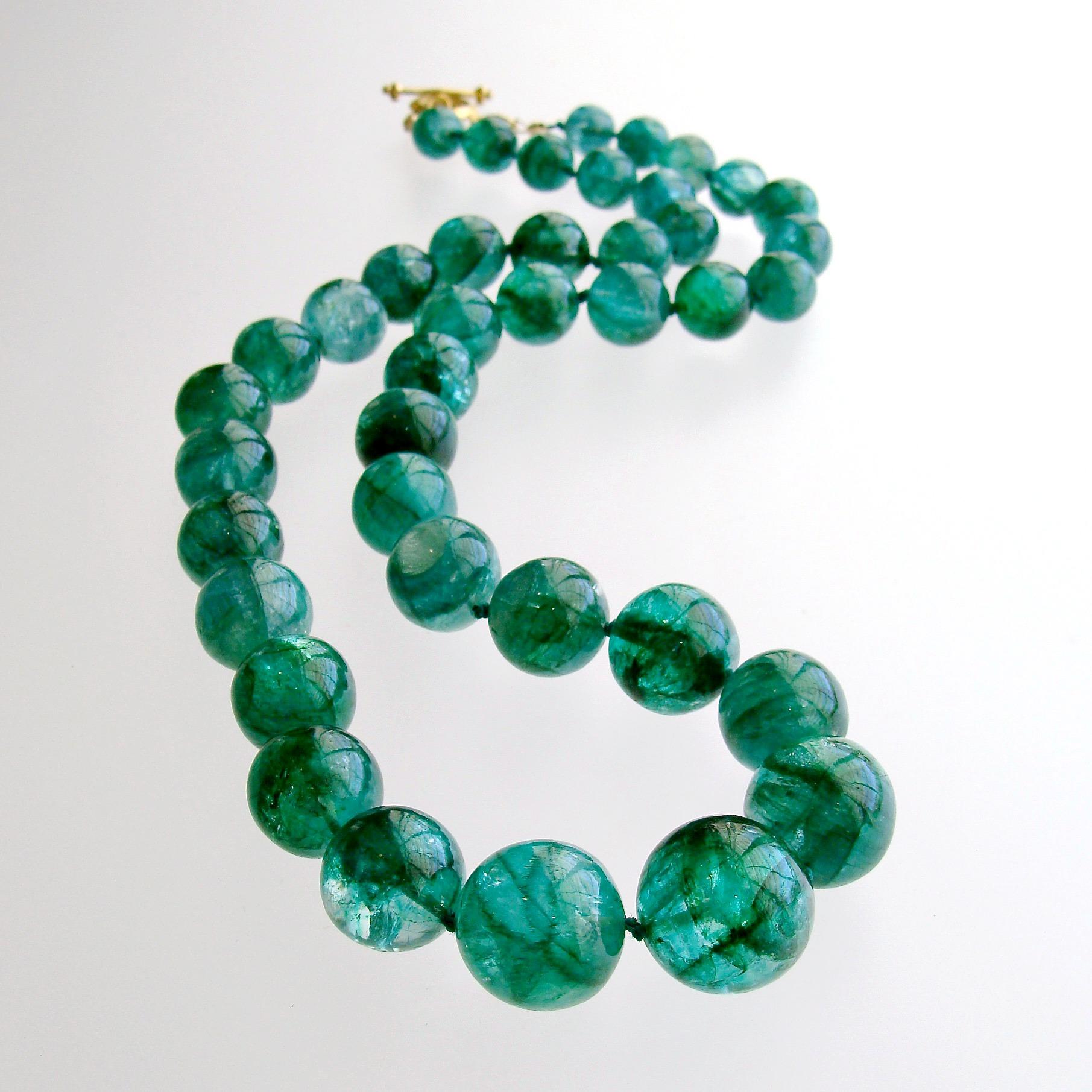 A luxe graduated strand of smooth and polished round emerald beads is hand-knotted with silk and completed with a 14k yellow gold toggle and findings to feature this remarkable green colored suite of natural emeralds.  This suite of emeralds, with