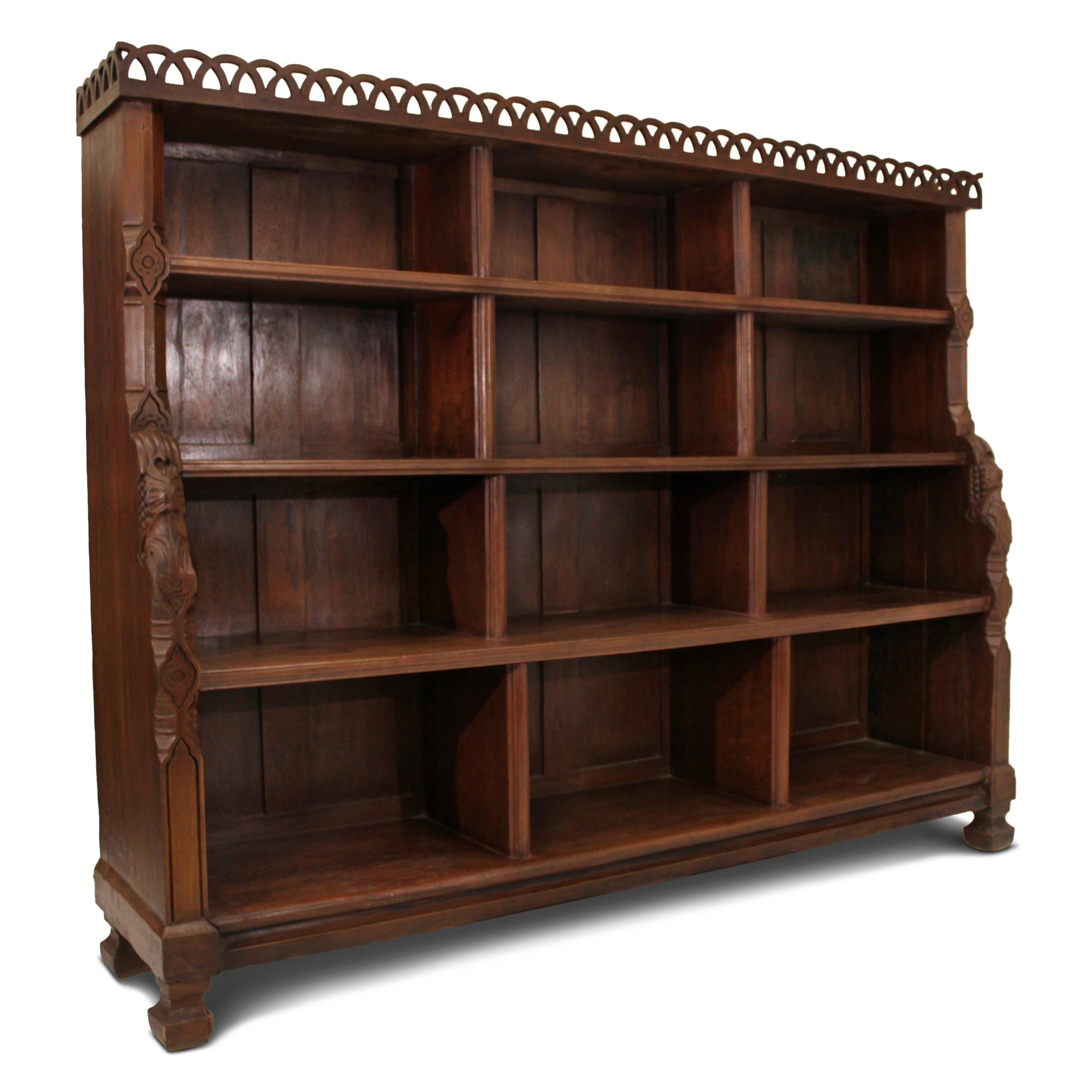 Teak bookcase, originating from an Indian palace library. This hand carved bookcase features thick, solid, graduated shelving and is adorned with a fret gallery on top.  
