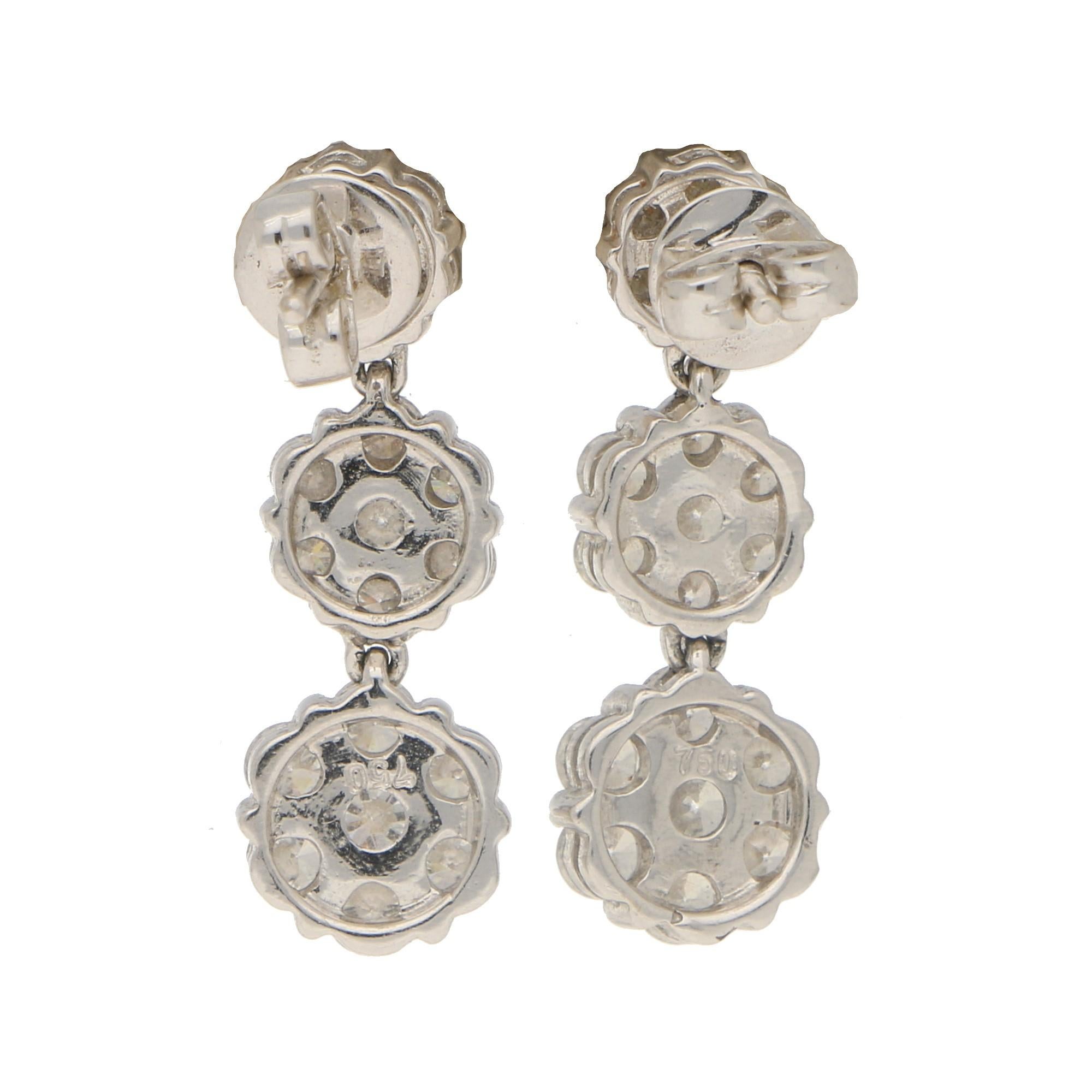 A beautiful little pair of diamond floral cluster drop earrings set in 18k white gold. Each earring is composed of three graduating floral clusters each connected by an articulated hoop allowing the drops to move nicely once on the ear. Each cluster