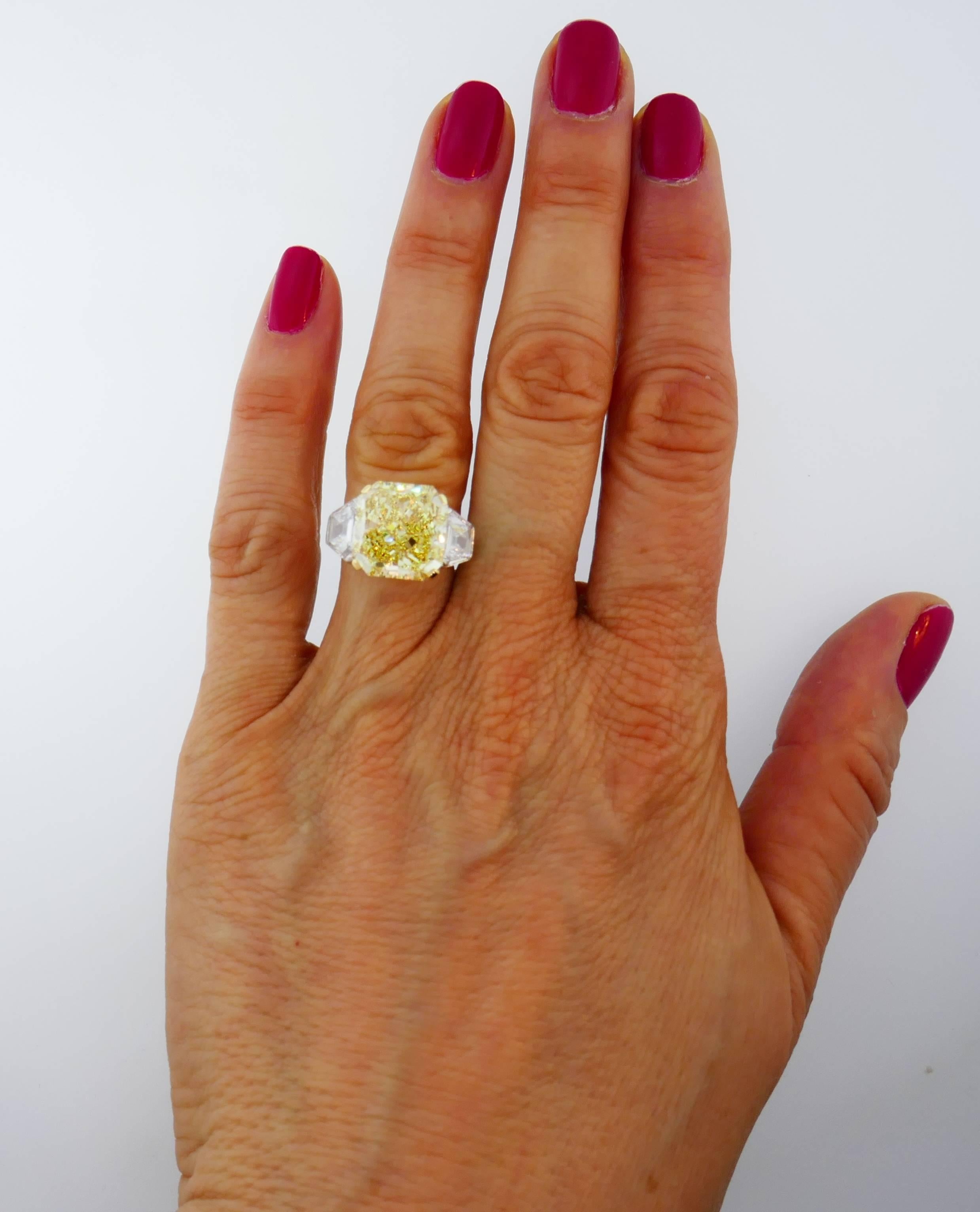 Magnificent diamond three-stone ring created by Lawrence Graff. Features a 10.62-carat natural fancy yellow cut-cornered square modified brilliant cut diamond flanked by two calf's head shape faceted white diamonds. The fancy yellow diamond comes