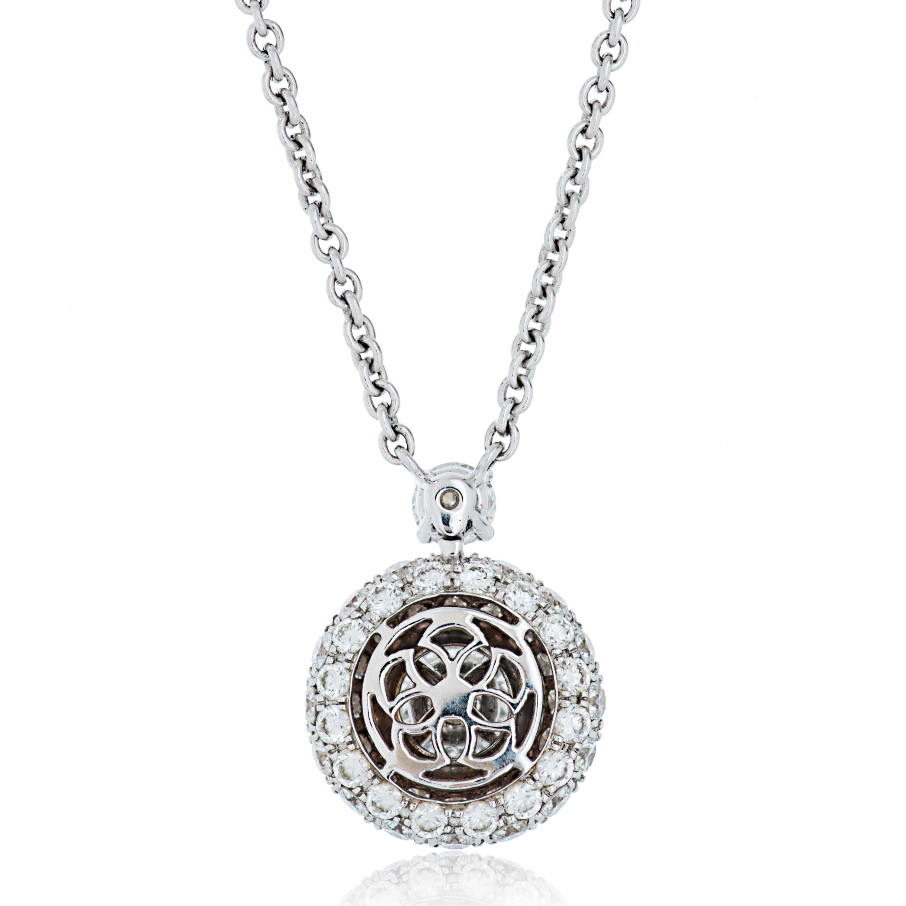 Si tratta di un pendente in oro bianco 18 carati con diamante Graff, caratterizzato da un diamante brillante rotondo centrale circondato da un'aureola di diamanti più piccoli incastonati, sospeso a una delicata catenina con un ulteriore diamante