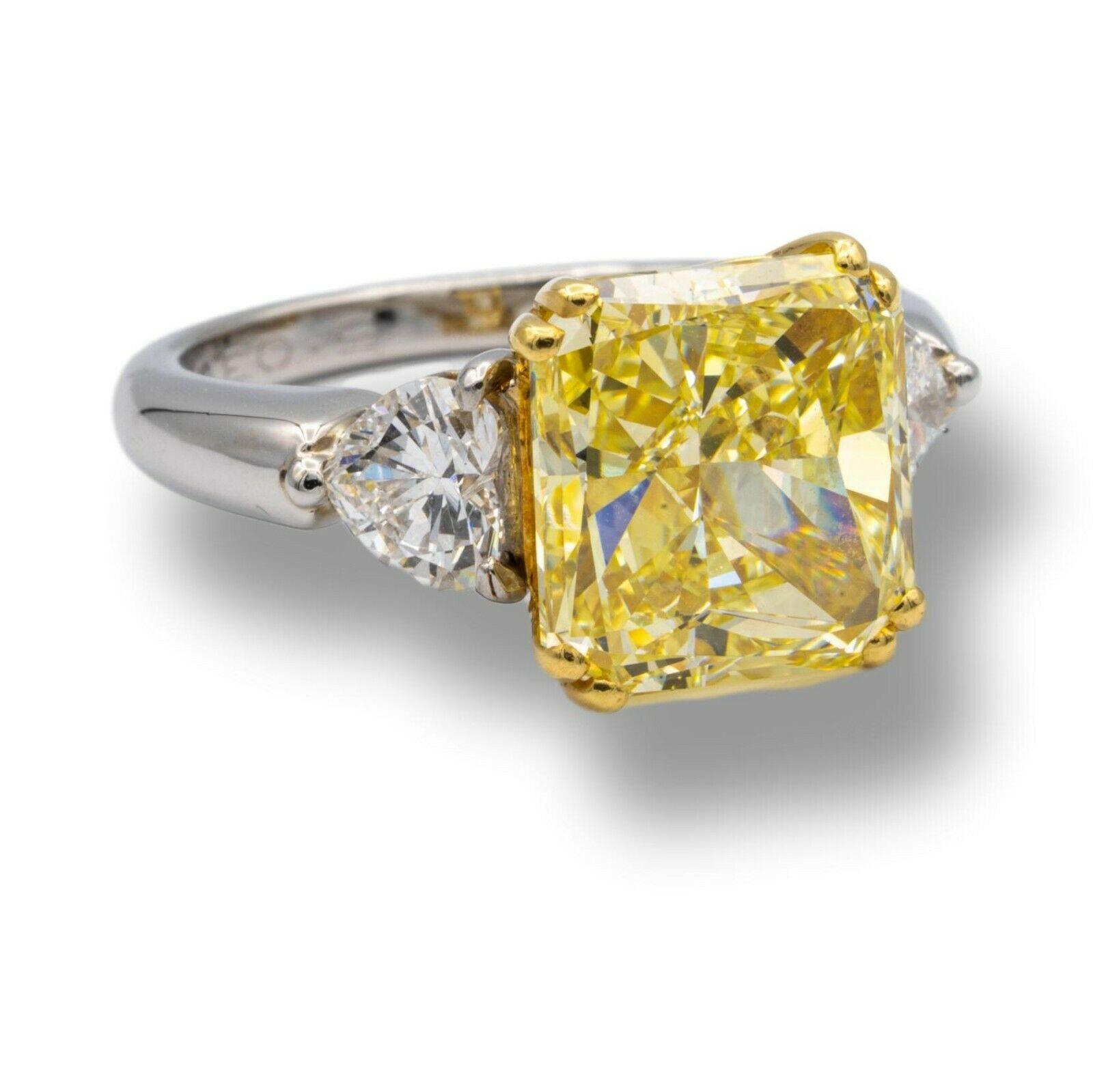 Three-Stone Estate Engagement Ring signed by Graff with a 5.03 ct. radiant cut fancy intense yellow diamond with VS2 clarity graded by GIA, finely crafted and set in 18 karat yellow gold prongs to enhance the beauty of the yellow diamond on top of a