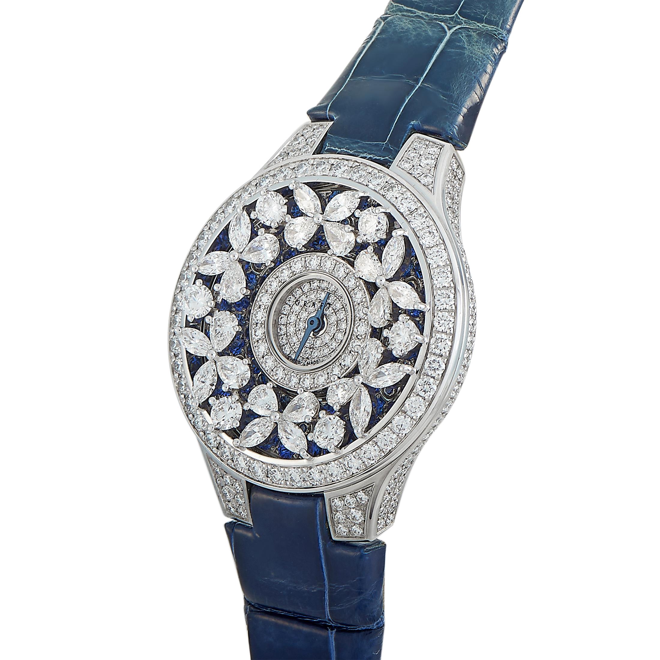 This is the Graff Butterfly watch, reference number BF32WGDS.

It is presented with a diamond-embellished 18K white gold case that measures 32 mm in diameter. The case is mounted onto a blue leather strap fitted with a diamond-set tang buckle. This